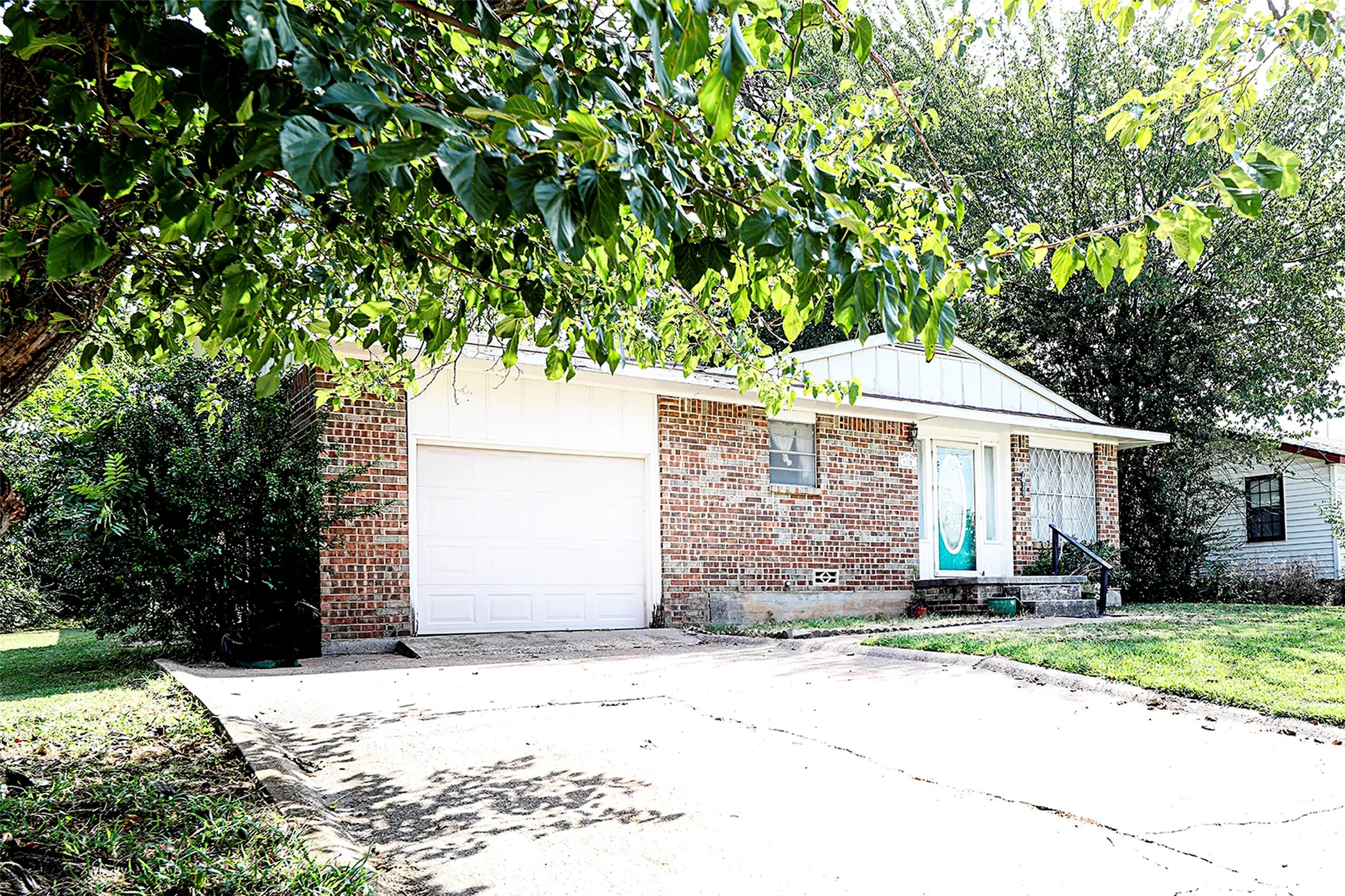 View of front of house featuring concrete driveway, brick siding, an attached garage, and a front lawn
