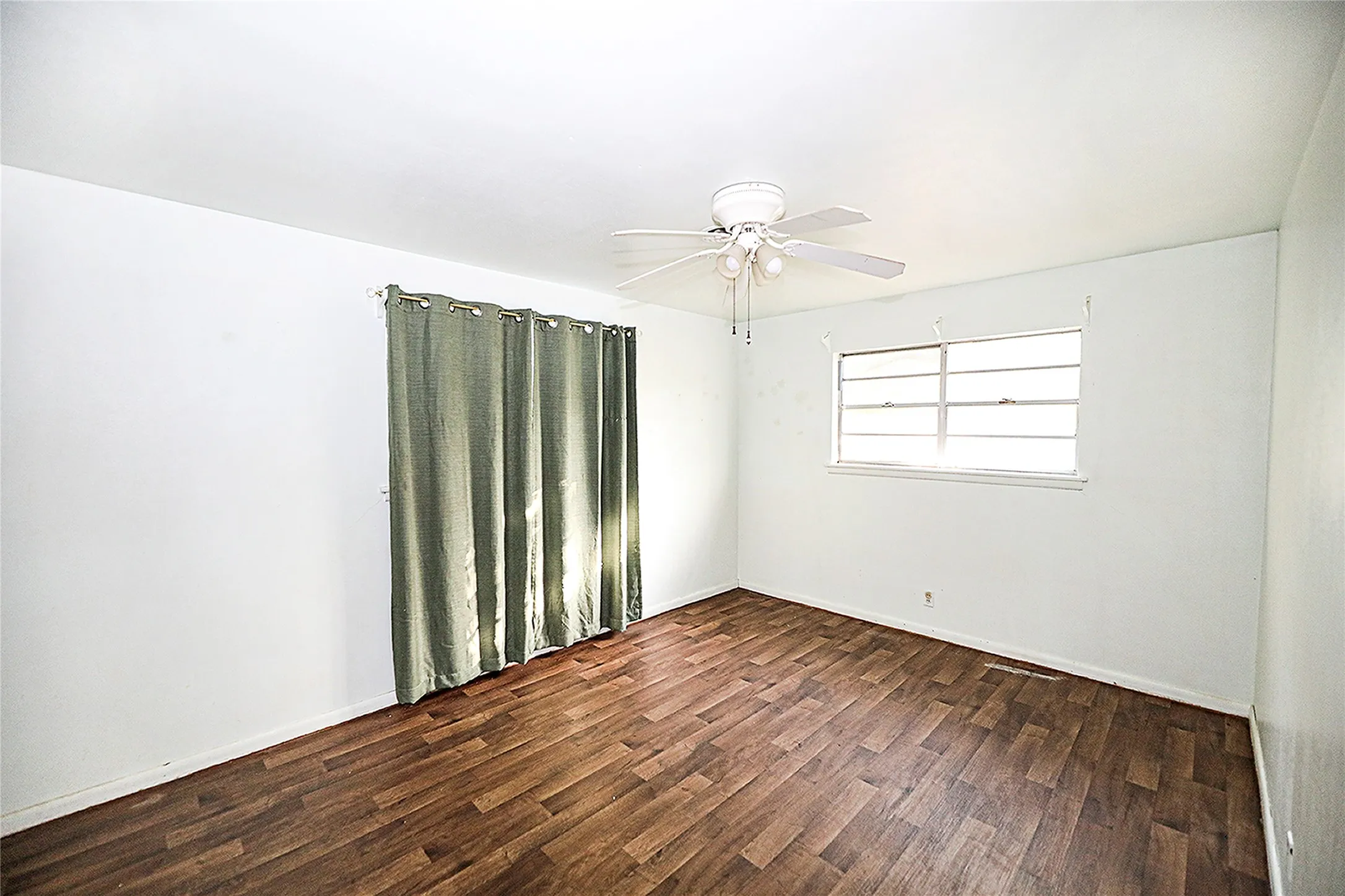 Empty room featuring dark wood-style floors and ceiling fan
