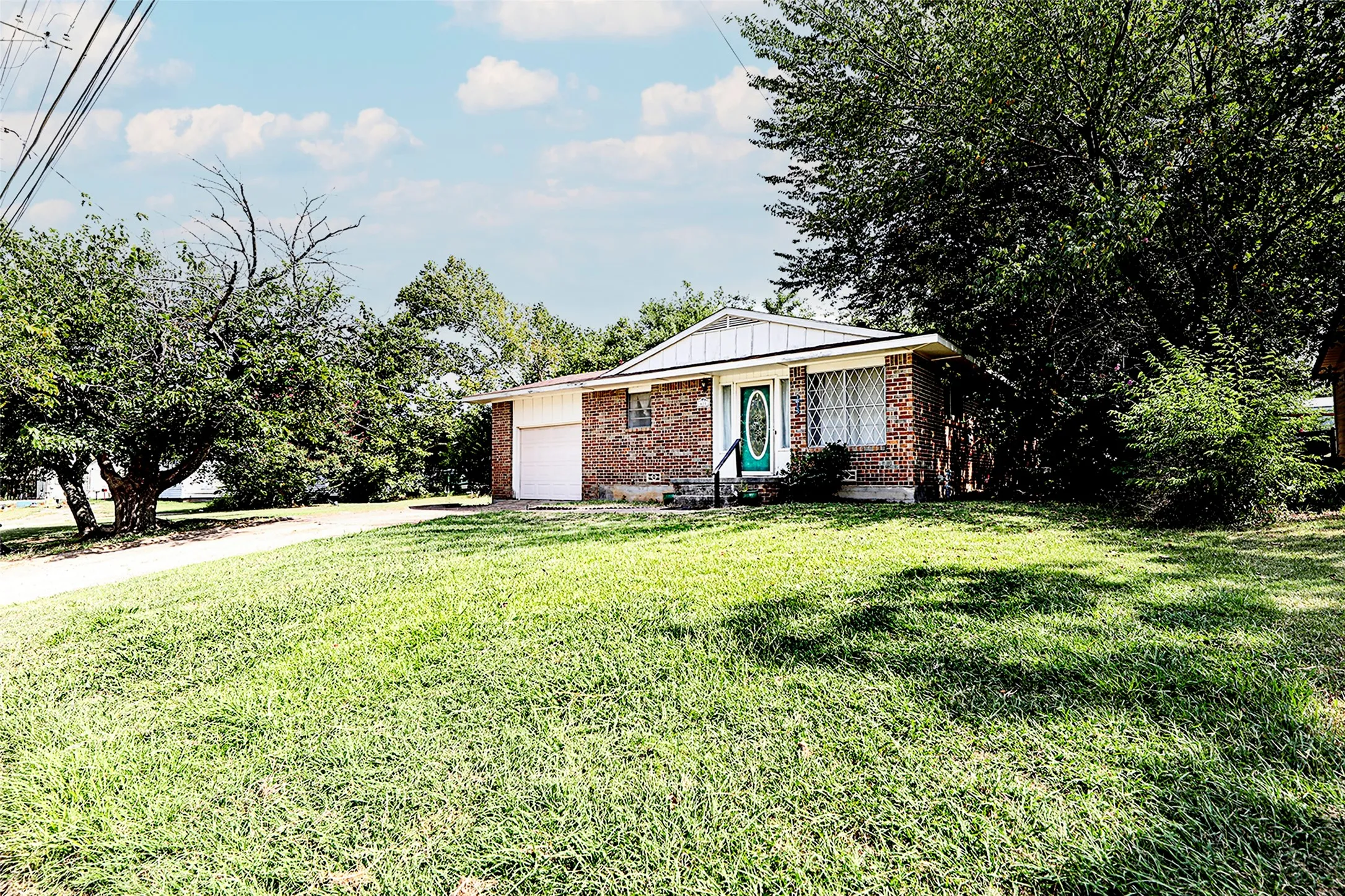 Ranch-style home with driveway, an attached garage, board and batten siding, a front yard, and brick siding