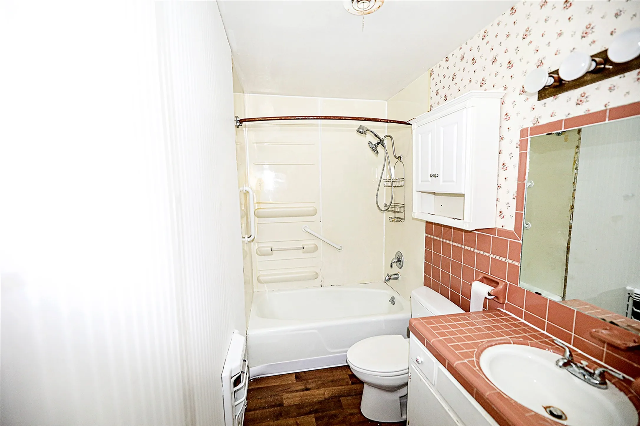 Full bathroom with shower / washtub combination, dark wood-style floors, vanity, backsplash, and wallpapered walls