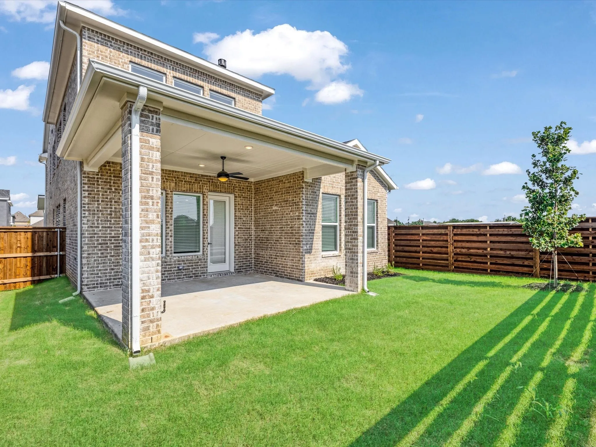 Back of property with a fenced backyard, a patio, a ceiling fan, and brick siding