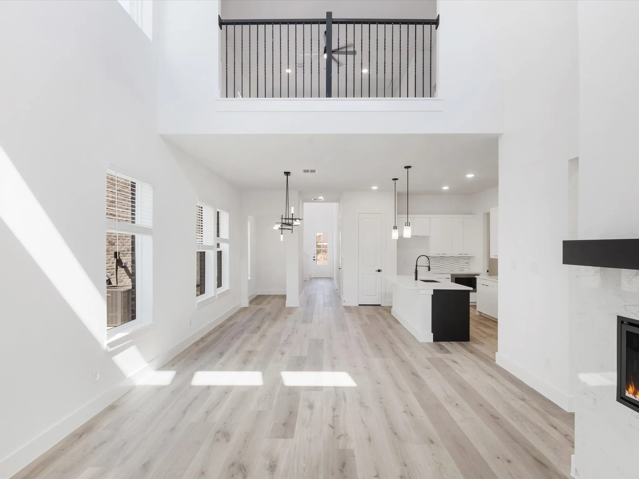 Unfurnished living room with a high ceiling, plenty of natural light, a high end fireplace, light wood-type flooring, and a chandelier