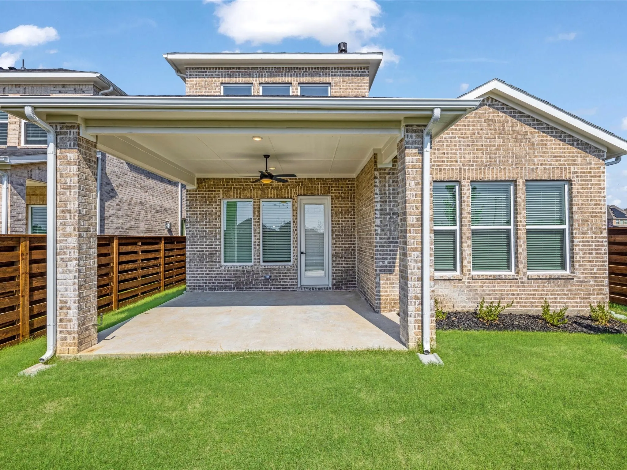 Rear view of house featuring ceiling fan, a patio area, and brick siding