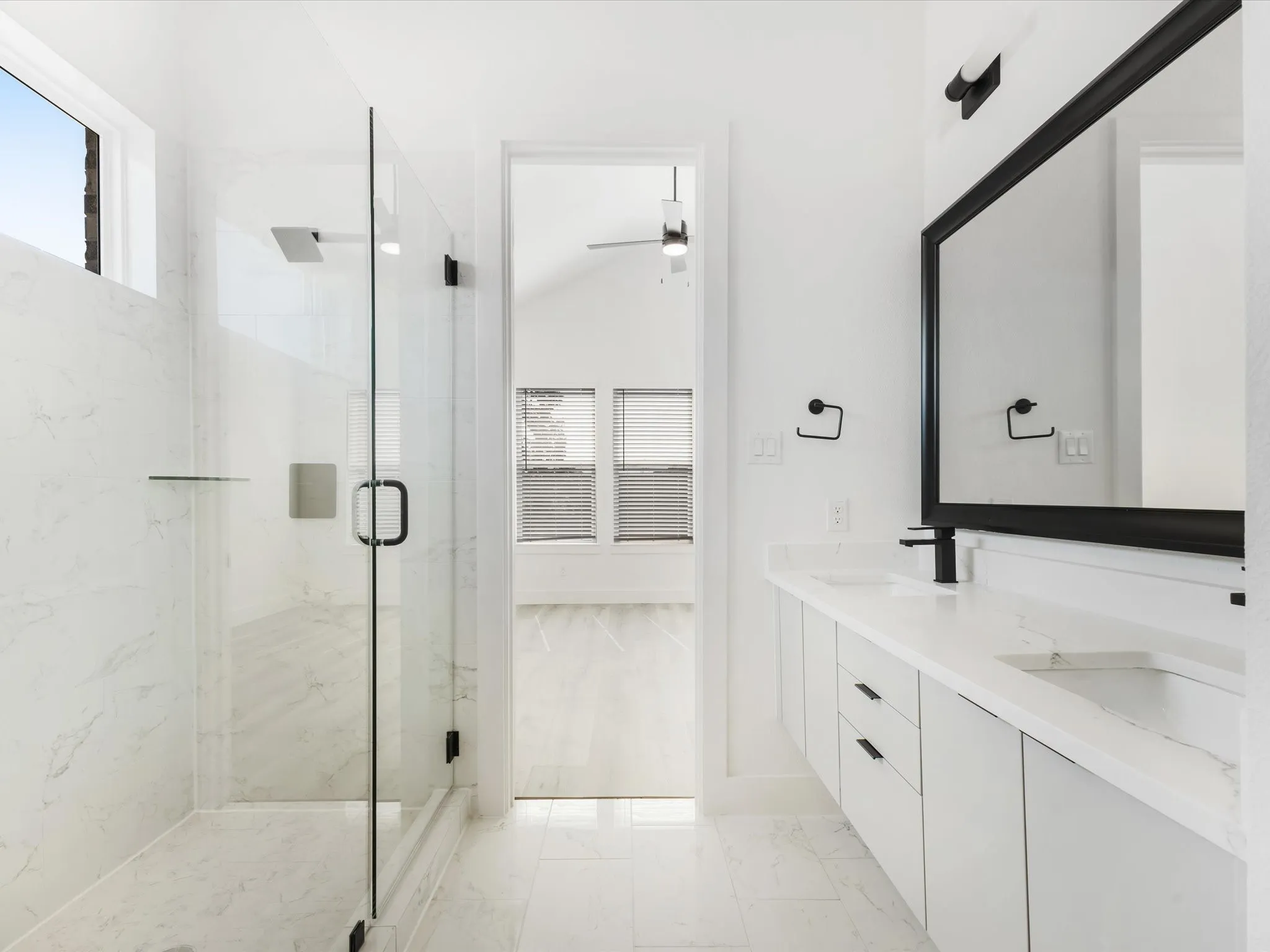 Bathroom featuring plenty of natural light, a marble finish shower, light marble finish floors, vaulted ceiling, and ceiling fan