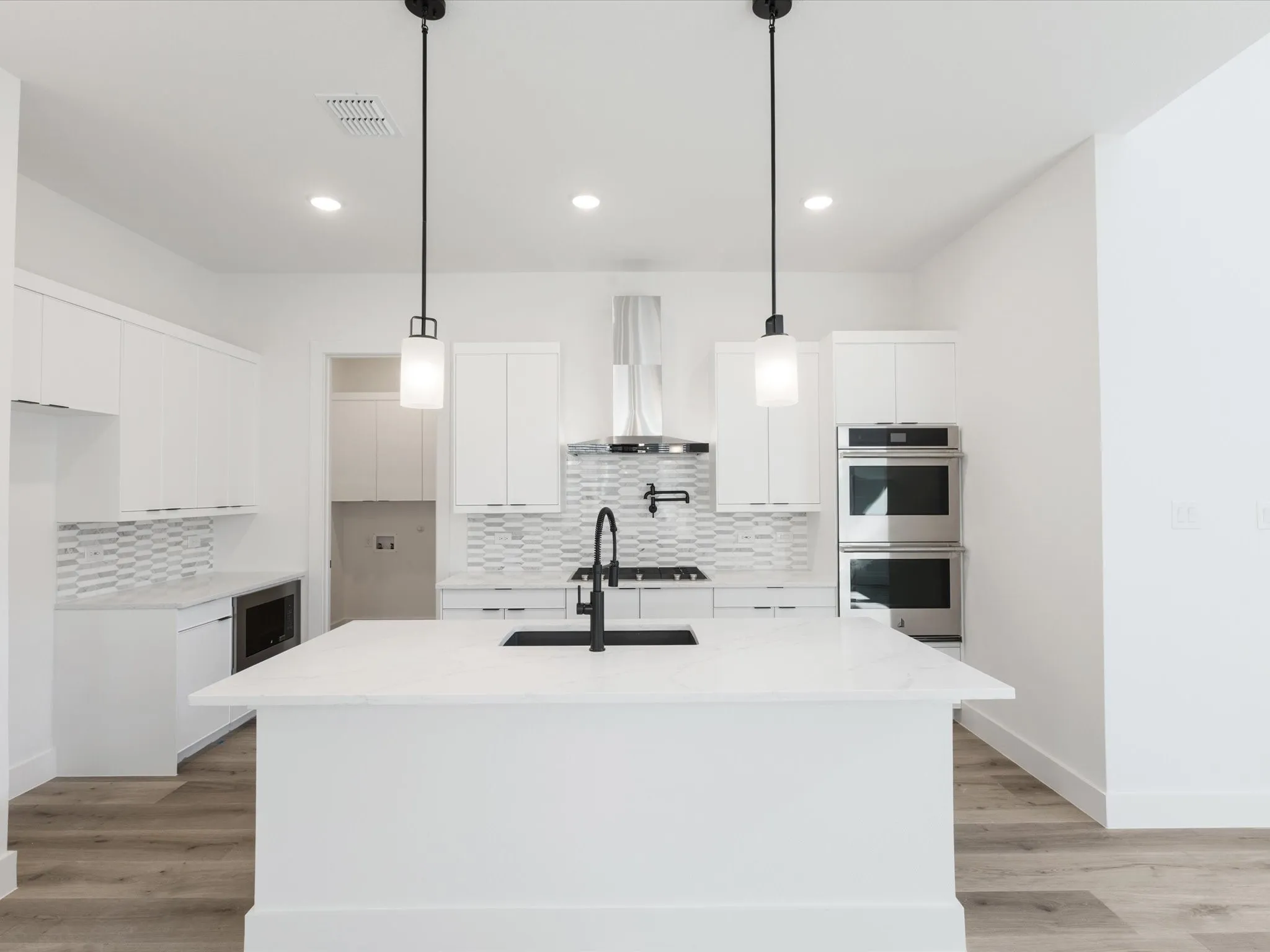 Kitchen featuring white cabinetry, pendant lighting, light stone countertops, double oven, and light wood-type flooring