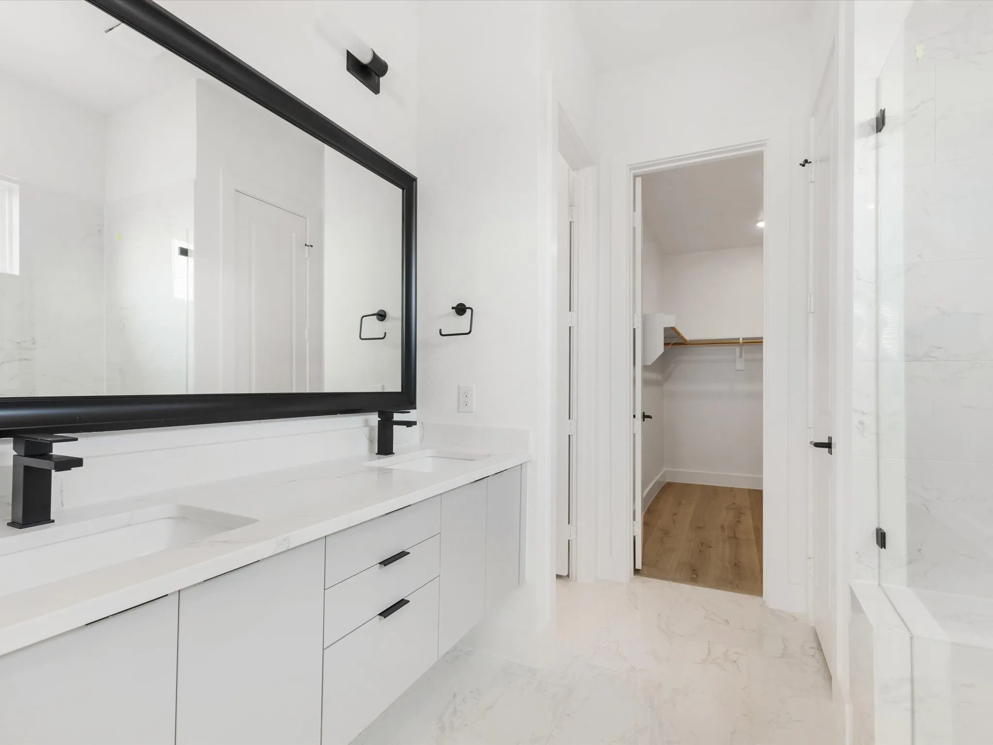 Full bath featuring a spacious closet, light marble finish floors, and a marble finish shower