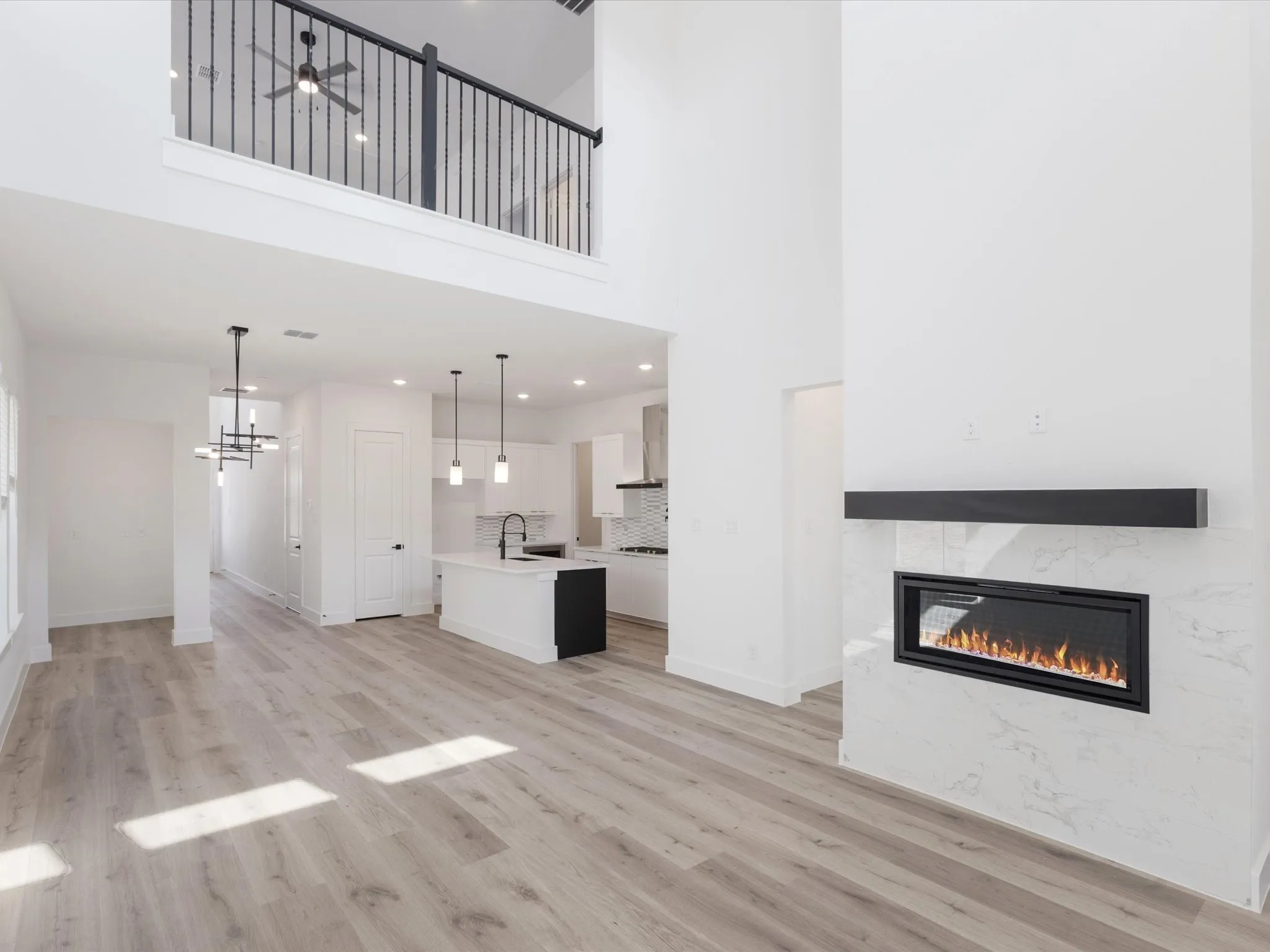 Unfurnished living room with a fireplace, a towering ceiling, light wood-type flooring, a chandelier, and recessed lighting
