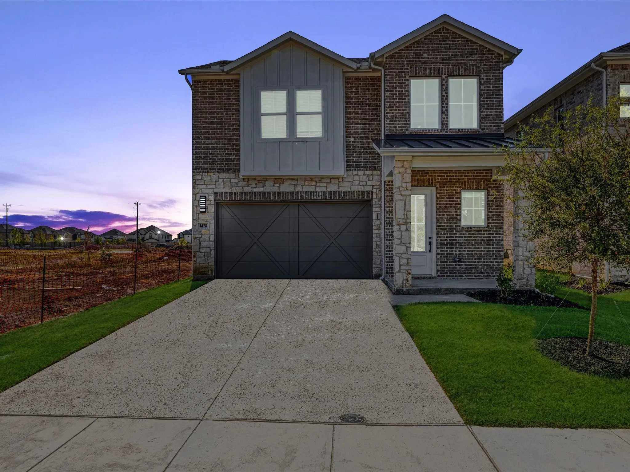 View of front of property with stone siding, an attached garage, driveway, board and batten siding, and a porch