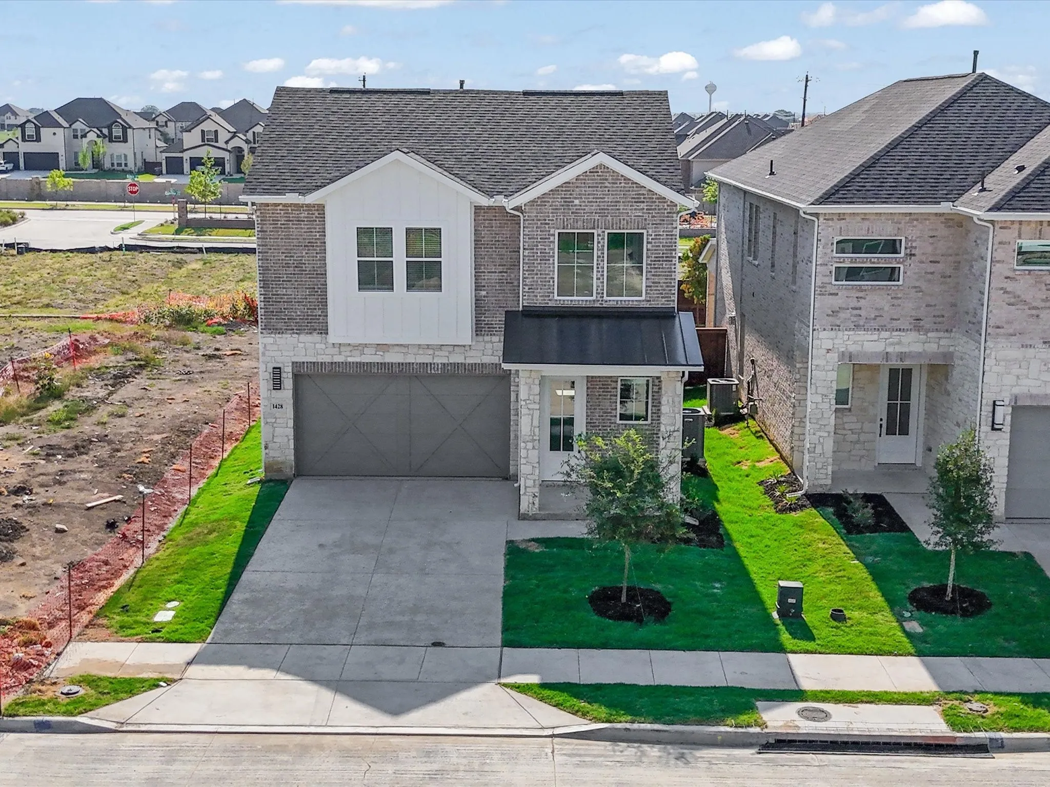 View of front of house featuring a residential view, an attached garage, stone siding, driveway, and a front yard