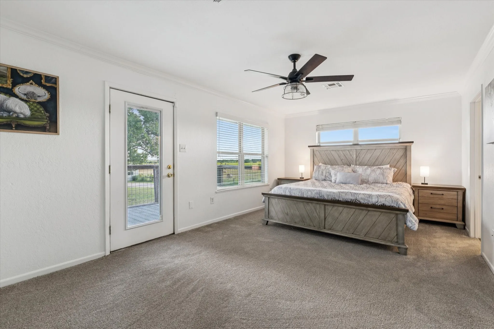 Carpeted bedroom with multiple windows, access to outside, ornamental molding, and a ceiling fan
