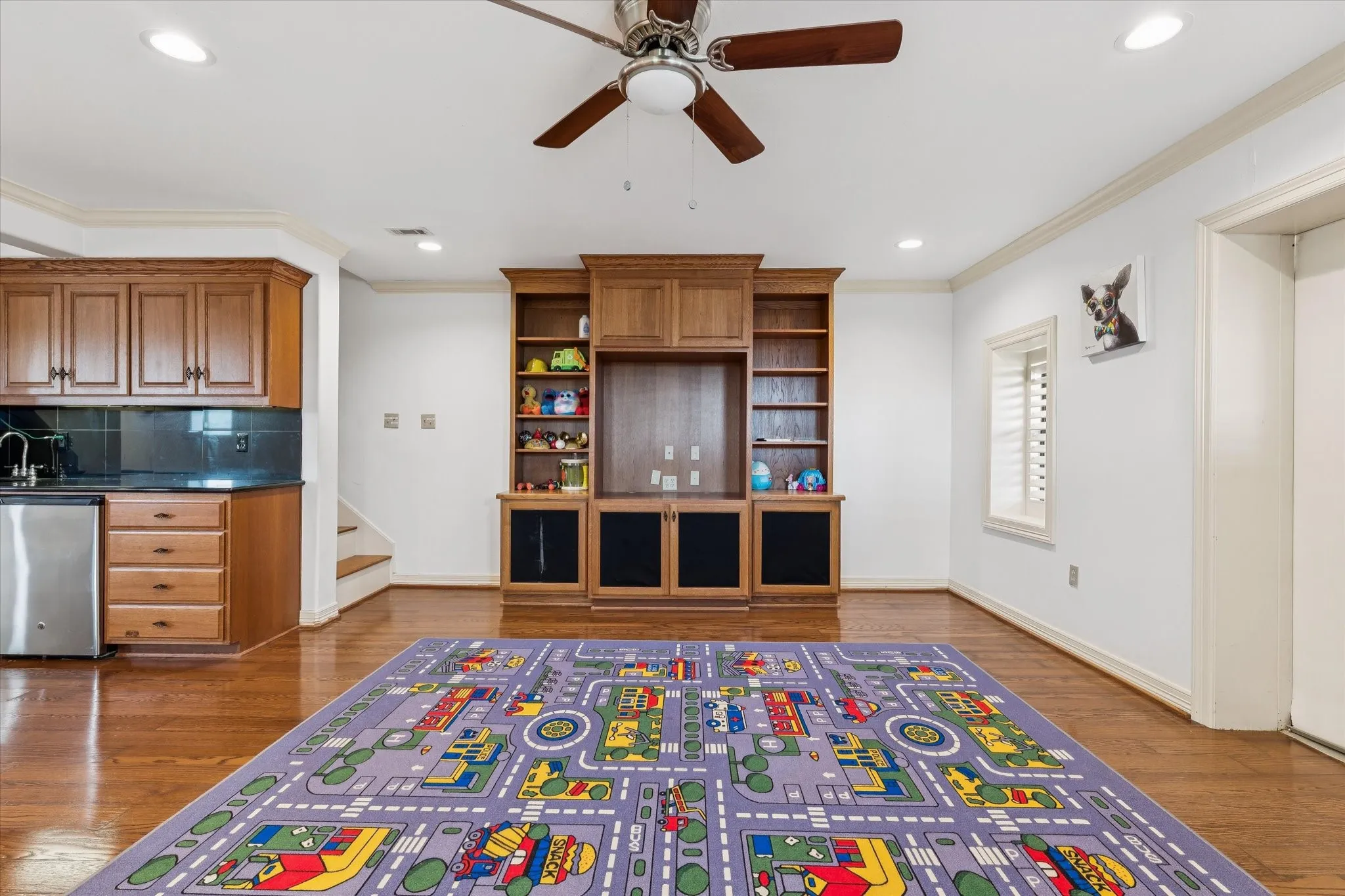 Living room featuring dark wood finished floors, recessed lighting, a ceiling fan, ornamental molding, and stairs