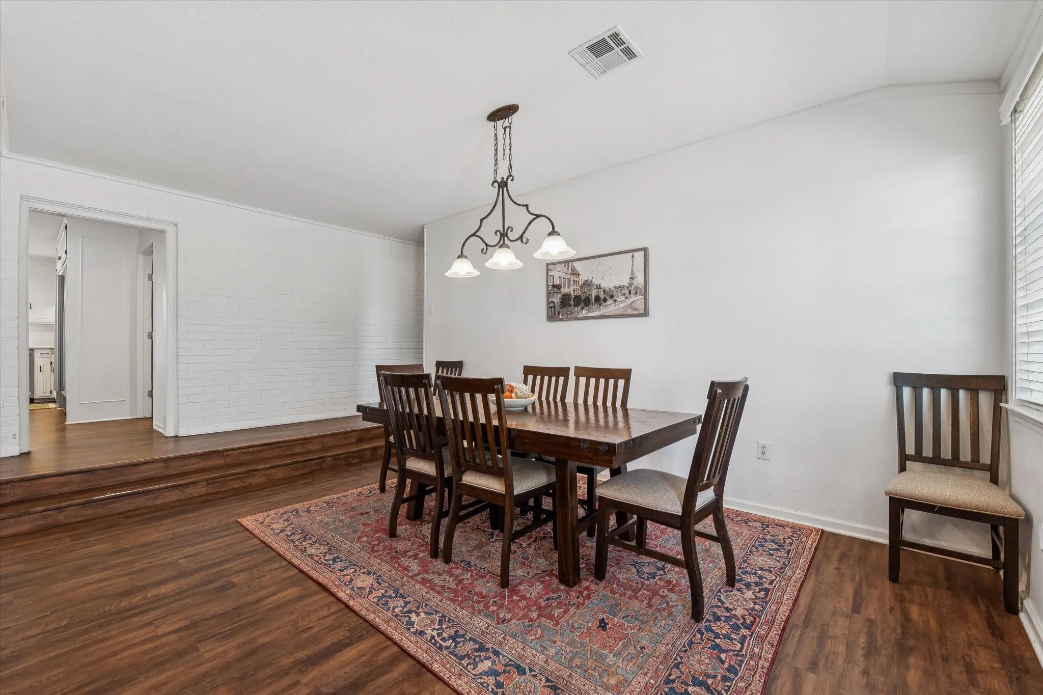 Dining area featuring dark wood-style flooring, a chandelier, plenty of natural light, and lofted ceiling