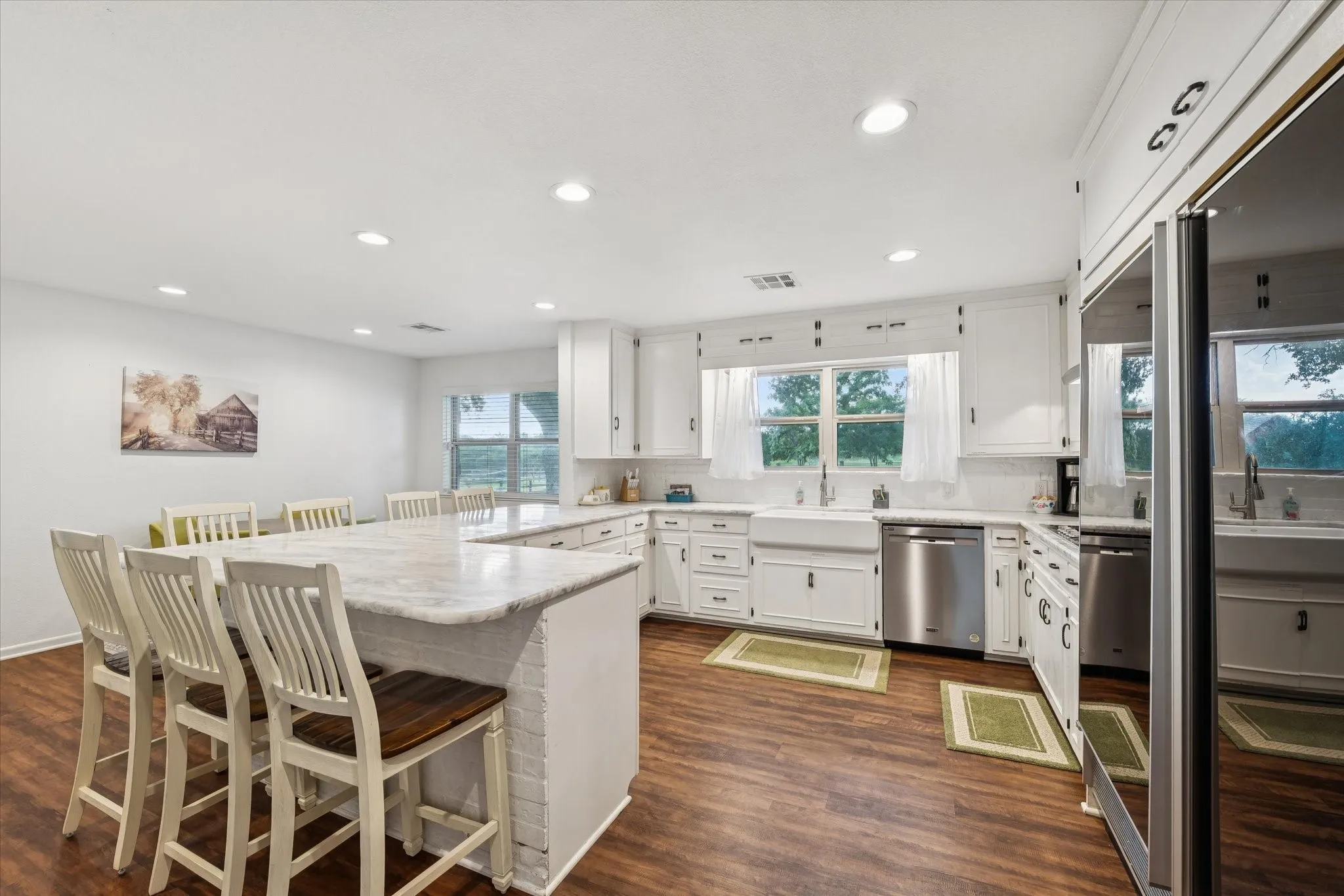 Kitchen featuring a kitchen breakfast bar, appliances with stainless steel finishes, white cabinetry, recessed lighting, and backsplash