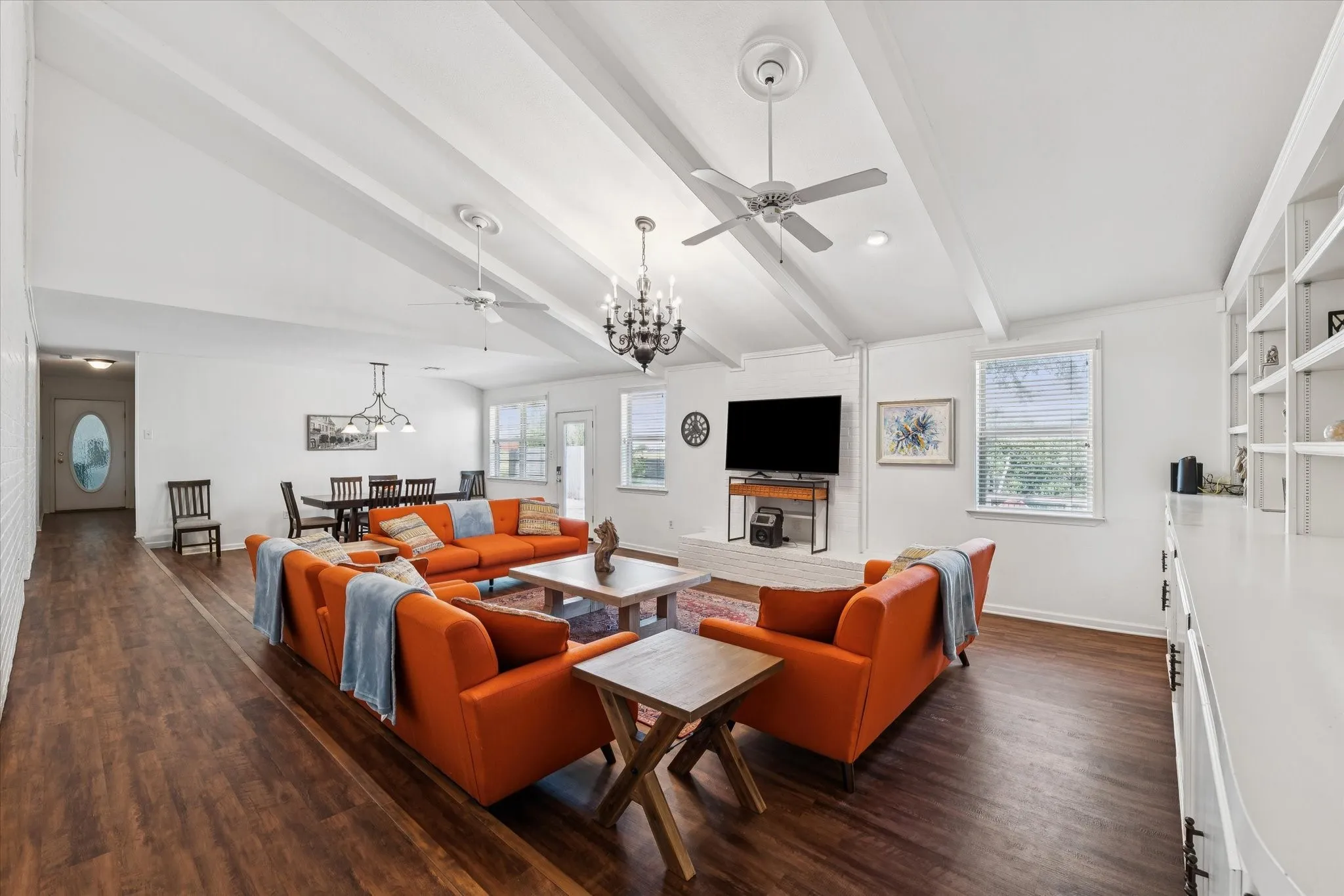 Living area with a chandelier, dark wood-style floors, and a ceiling fan
