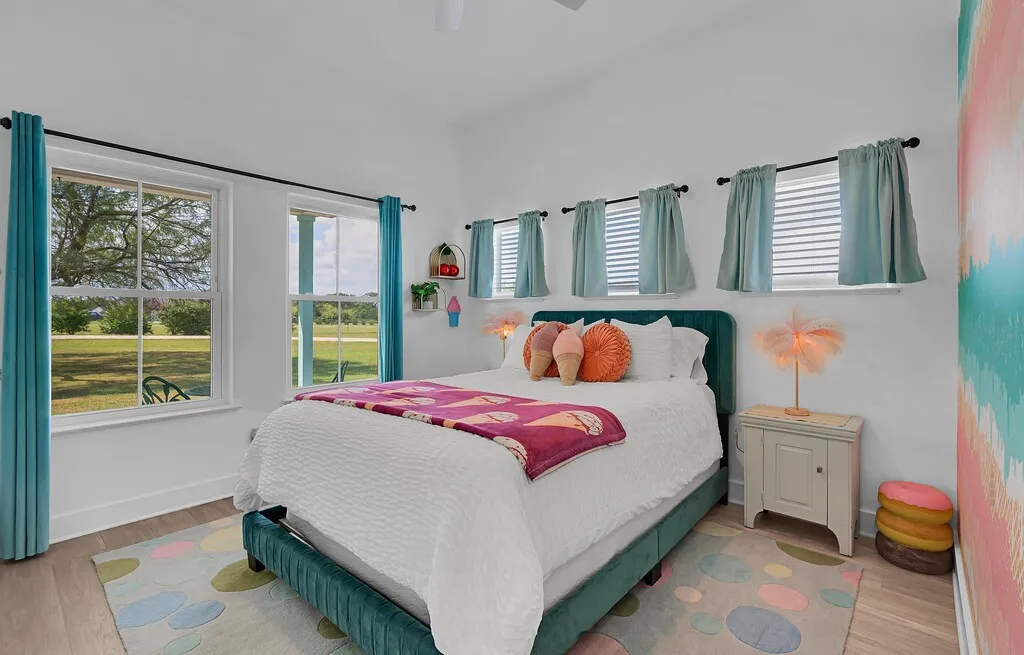 Bedroom featuring wood finished floors, multiple windows, and a ceiling fan