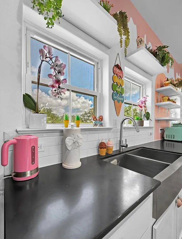 Kitchen featuring tasteful backsplash, dark countertops, white cabinetry, and open shelves