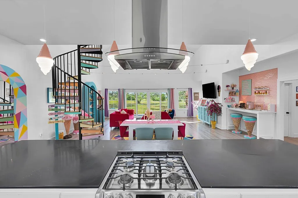 Kitchen with decorative light fixtures, island range hood, wood finished floors, stainless steel gas range, and recessed lighting