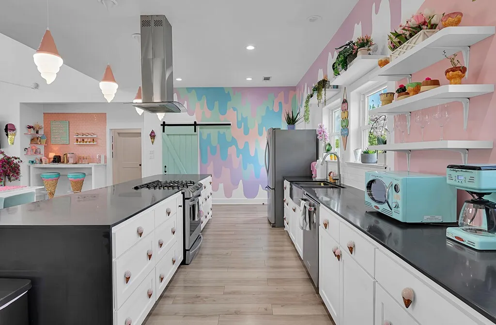 Kitchen featuring a barn door, open shelves, white cabinets, decorative light fixtures, and appliances with stainless steel finishes