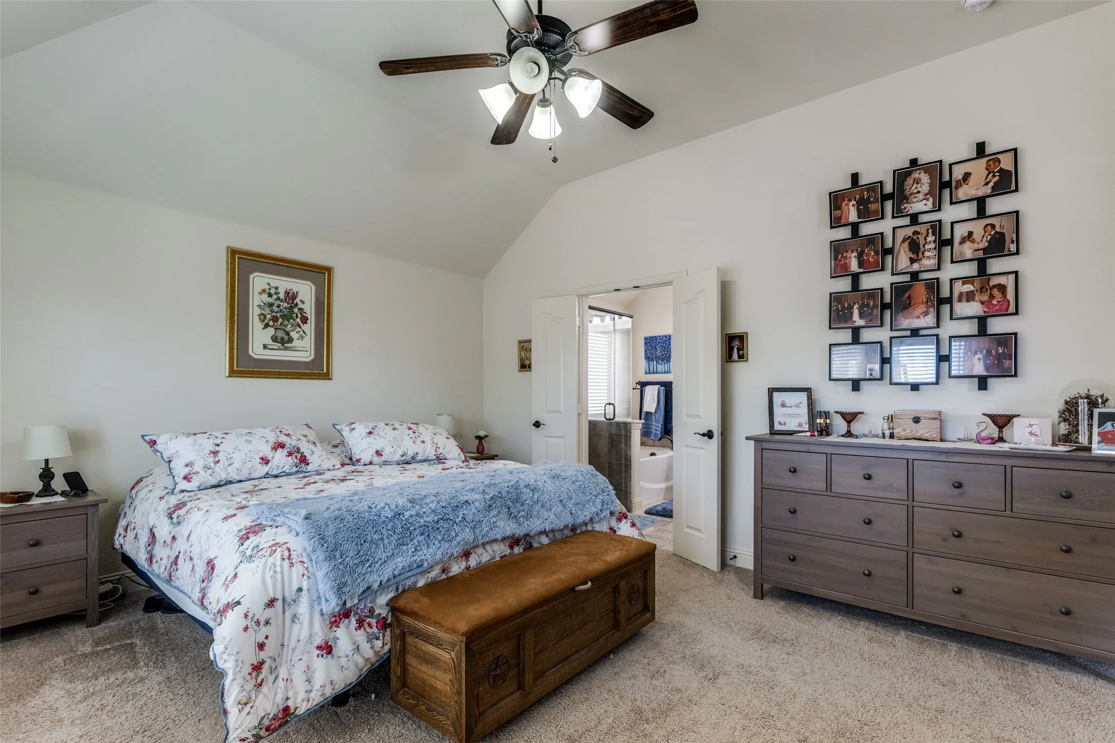 Bedroom with light carpet, vaulted ceiling, a ceiling fan, and ensuite bath