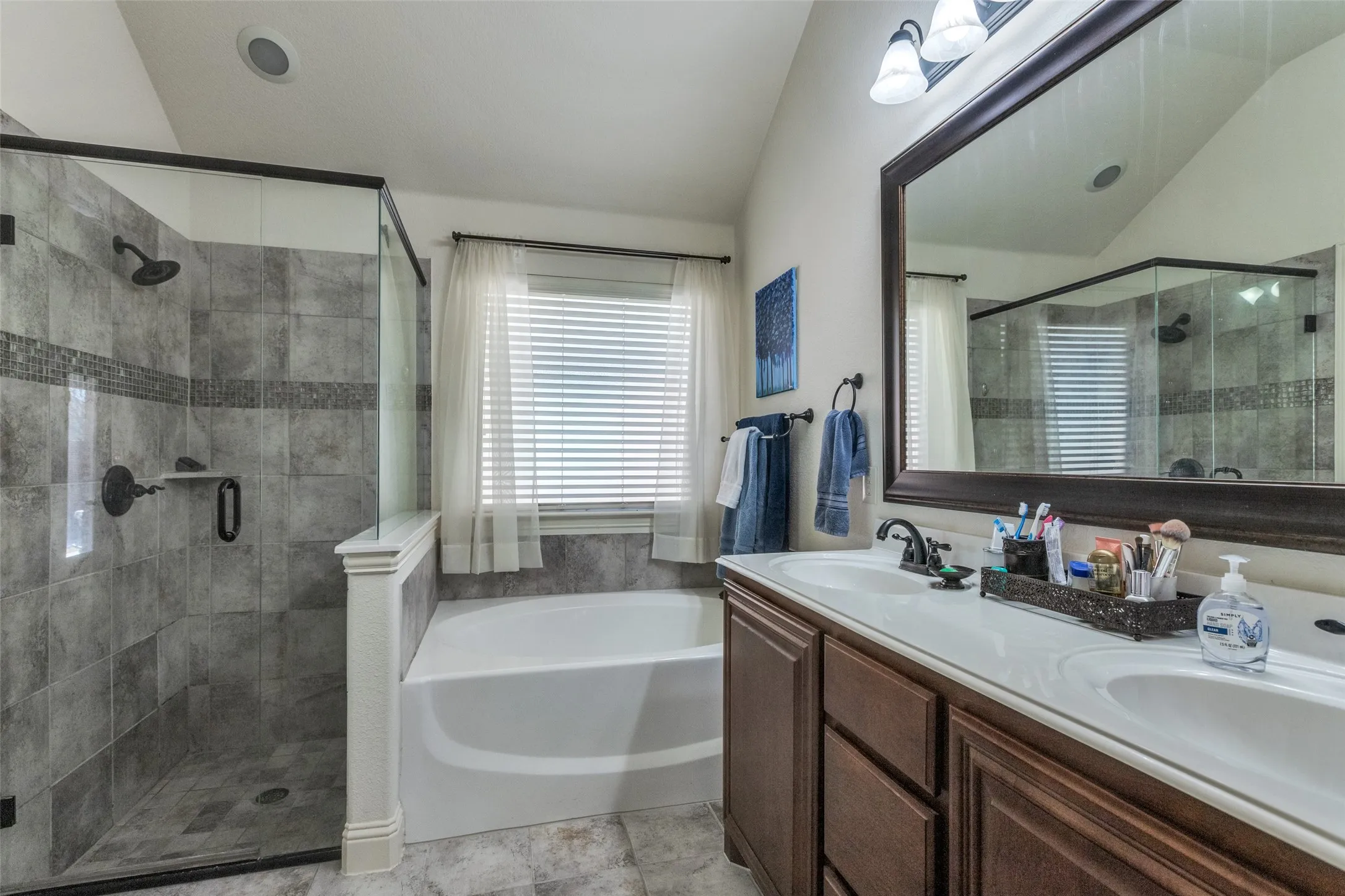 Full bath with a garden tub, lofted ceiling, a shower stall, and double vanity