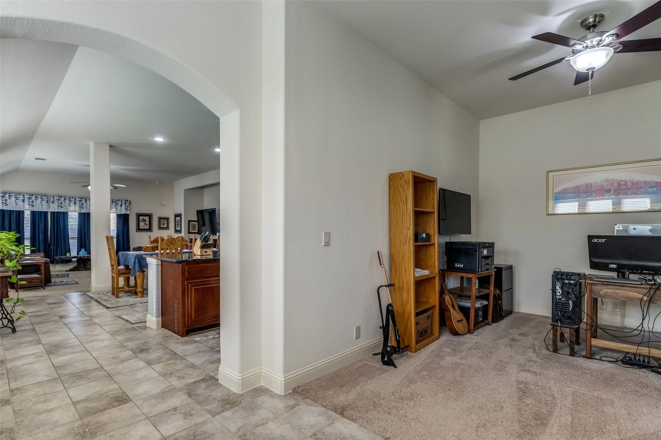 Living area featuring a ceiling fan, arched walkways, and light carpet