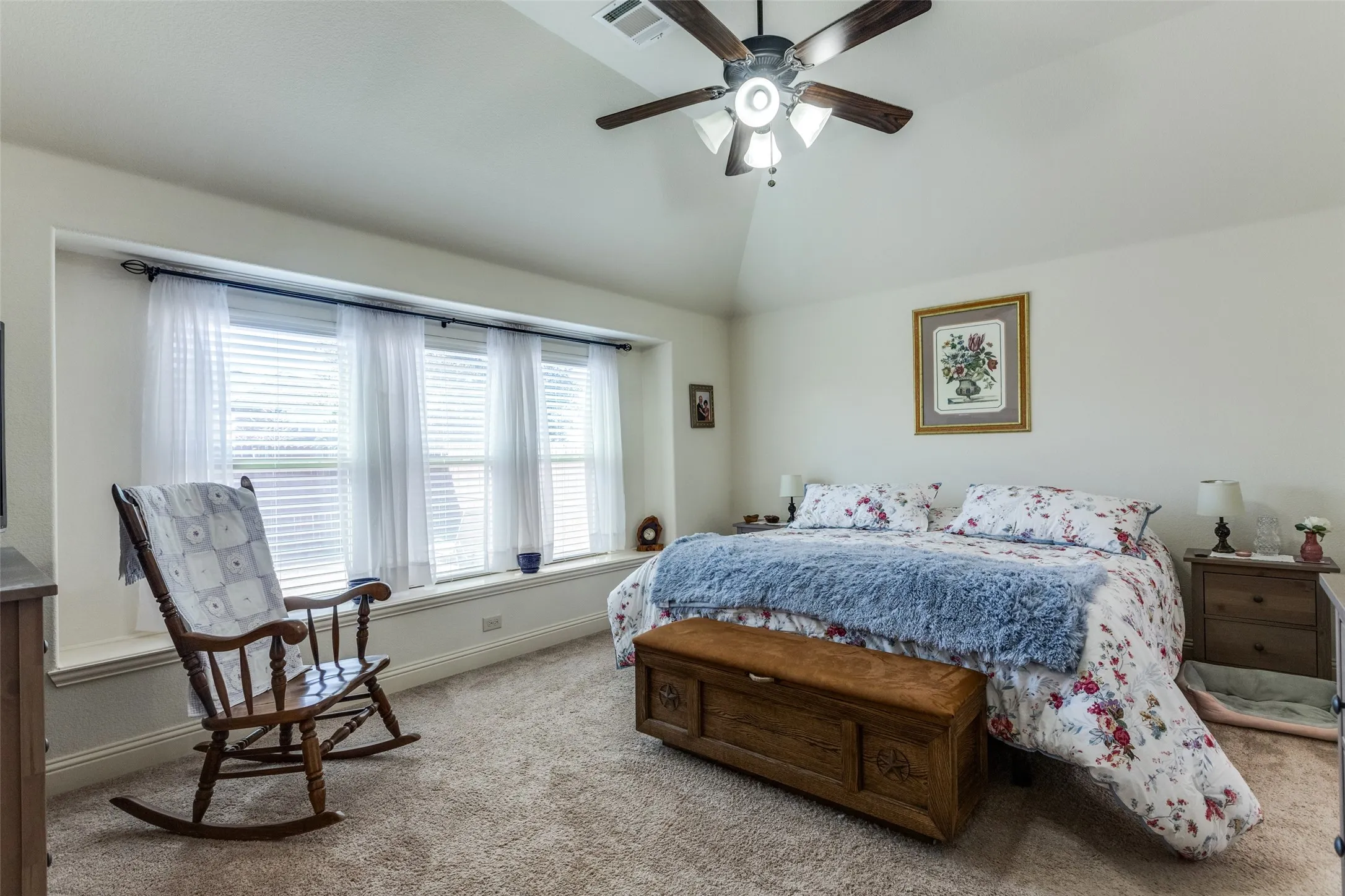 Carpeted bedroom with vaulted ceiling and a ceiling fan