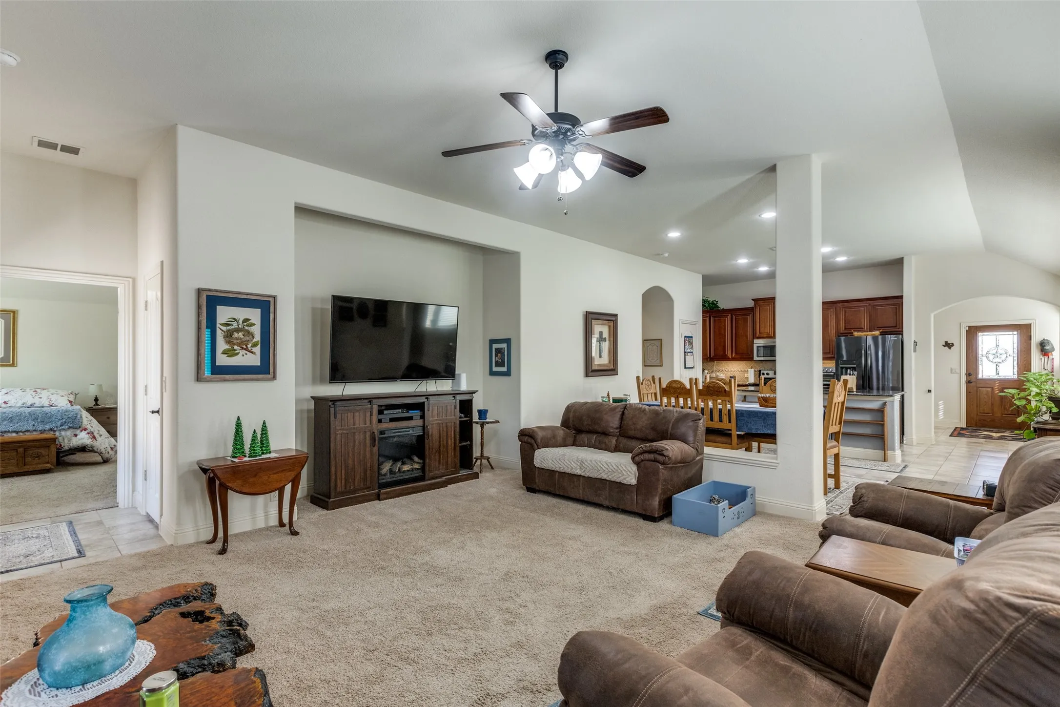 Living room featuring arched walkways, light colored carpet, recessed lighting, a ceiling fan, and light tile patterned flooring