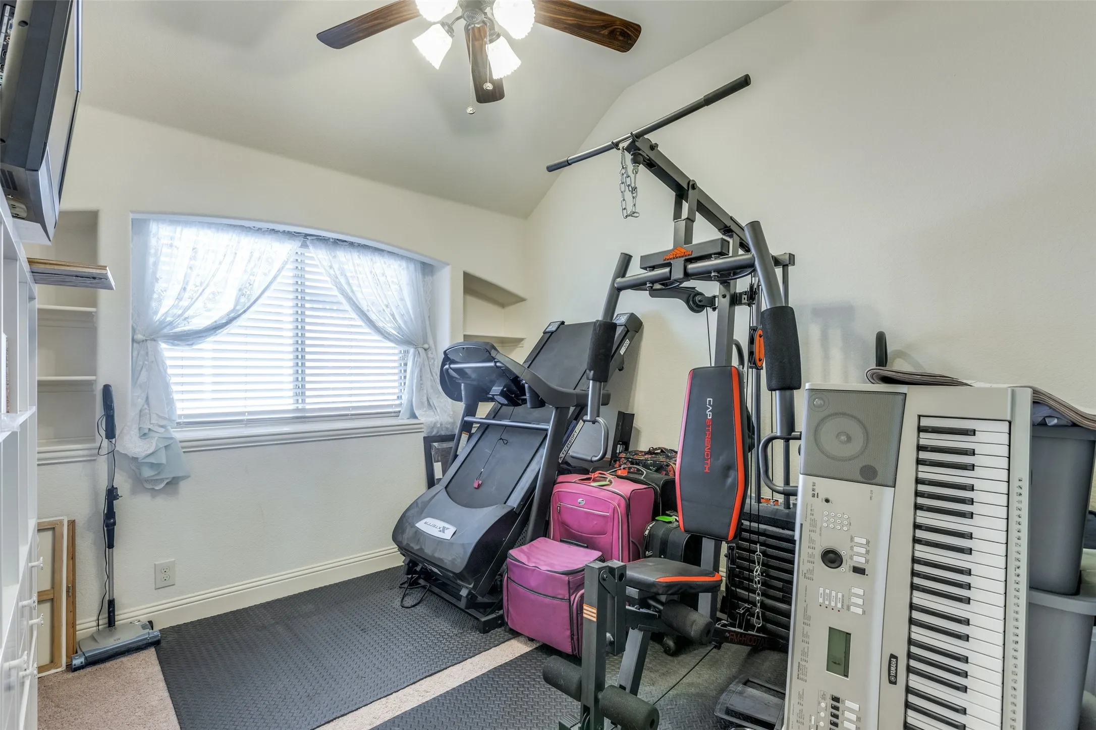 Workout area with ceiling fan, carpet, and vaulted ceiling