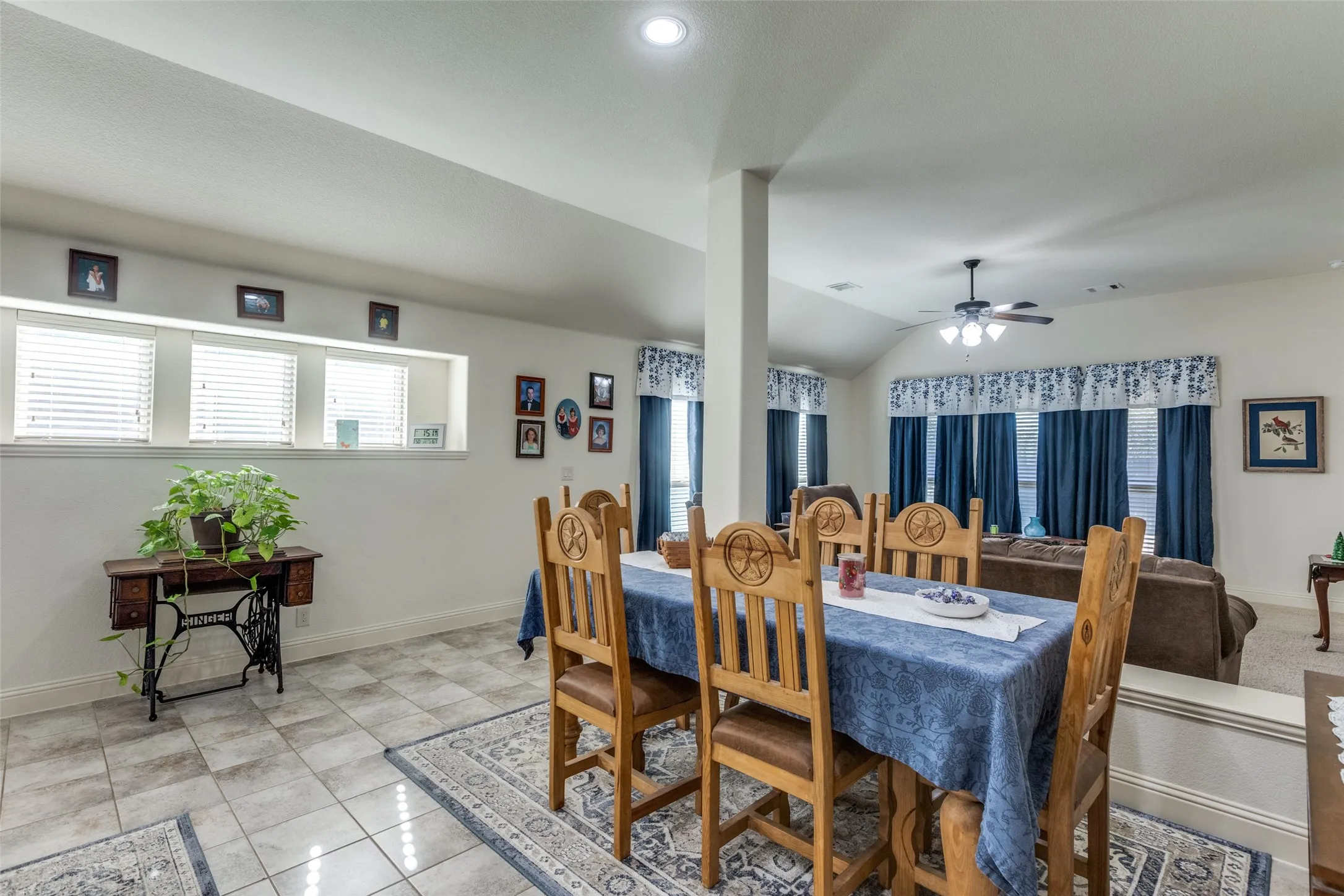 Dining space featuring lofted ceiling, plenty of natural light, ceiling fan, and light tile patterned flooring