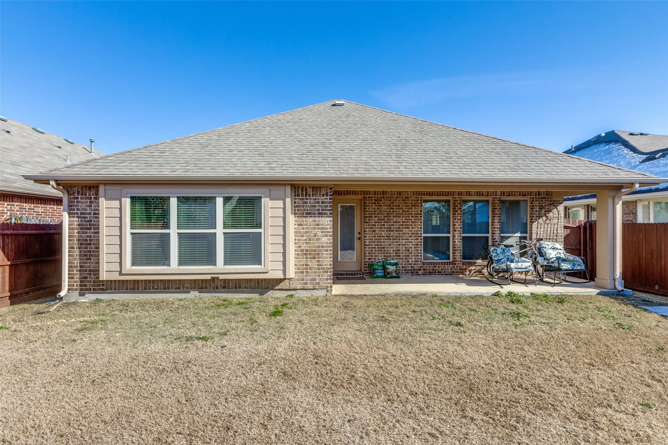 Rear view of property featuring roof with brick siding, and a covered patio