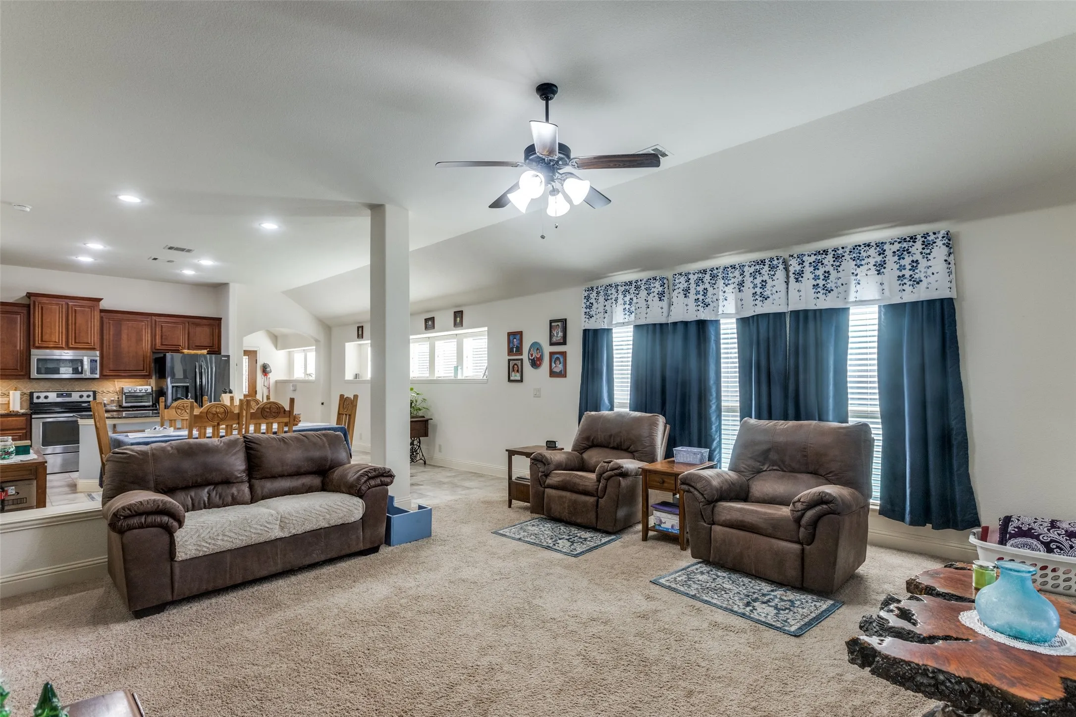 Living room featuring light colored carpet, healthy amount of natural light, a ceiling fan, recessed lighting, and vaulted ceiling