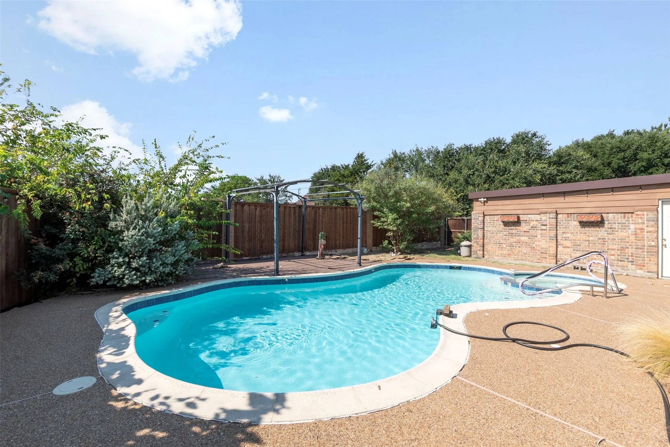 Freeform swimming pool with integrated spa and surrounding aggregate concrete decking