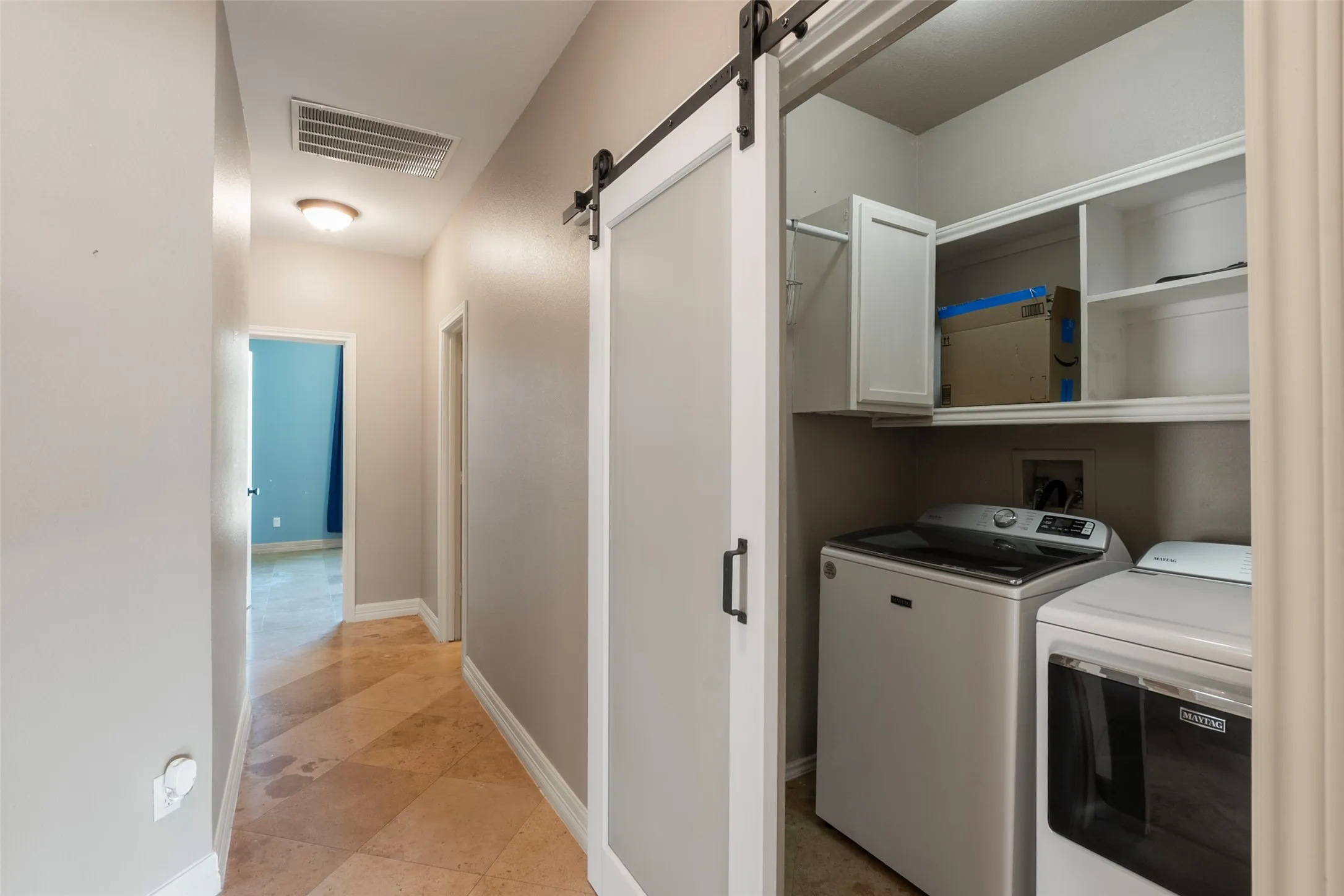 Hallway featuring tile flooring, neutral wall tones, and a laundry area with a barn door