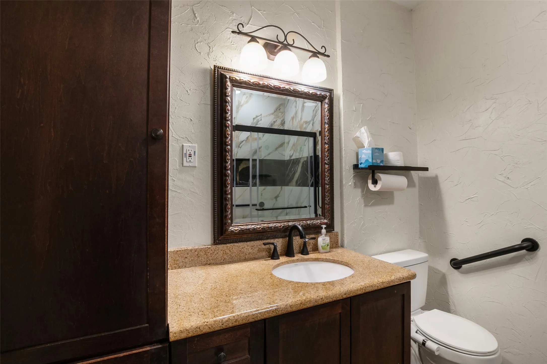 Dark wood vanity with a granite countertop, undermount sink, and oil-rubbed bronze faucet
