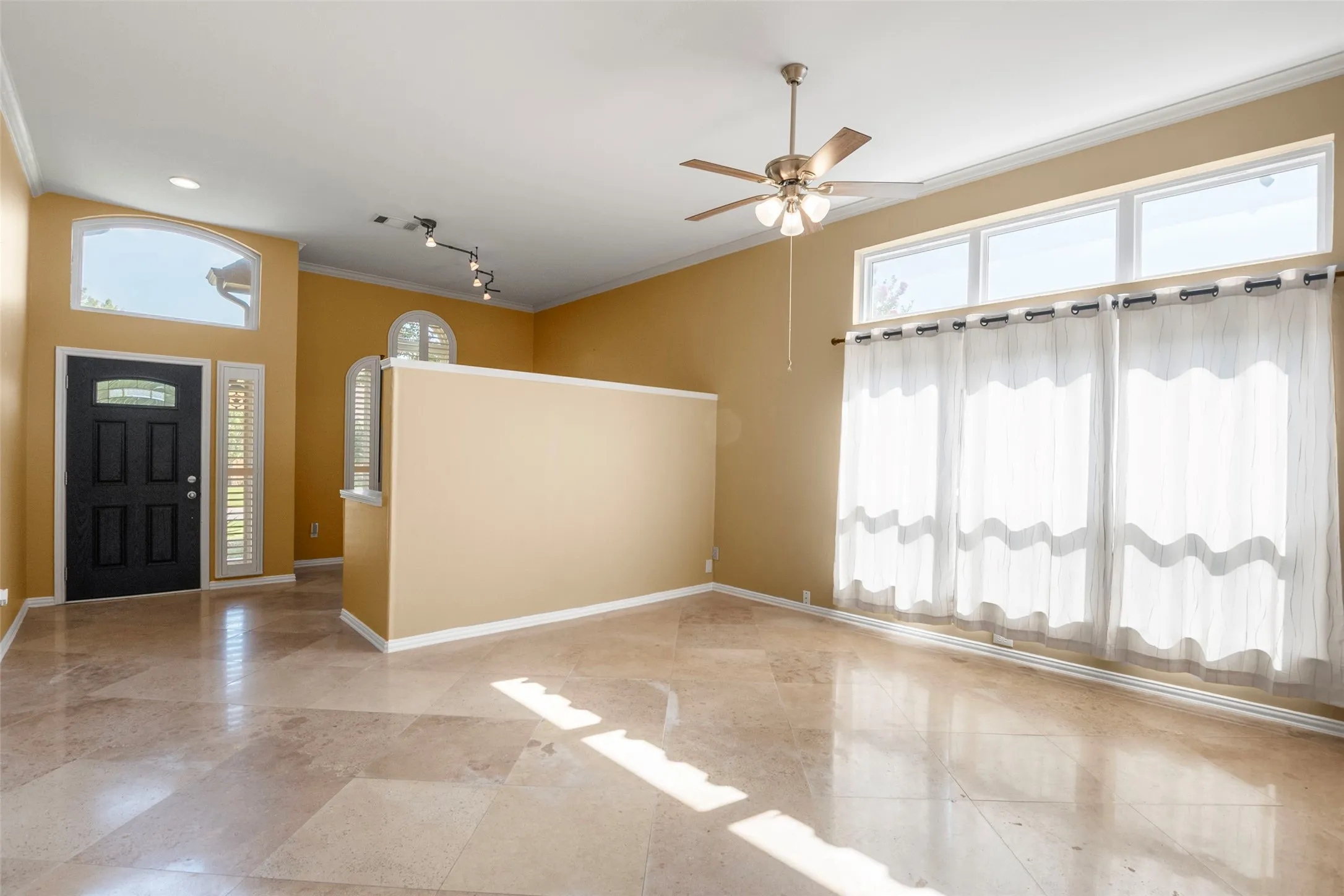 Polished tile flooring, high ceilings with crown molding, and a ceiling fan