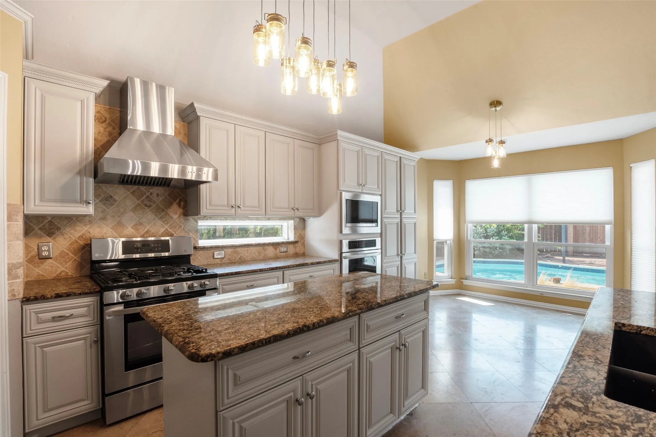 Kitchen featuring a central island with countertop, stainless steel appliances, light-toned cabinetry, and a vaulted ceiling