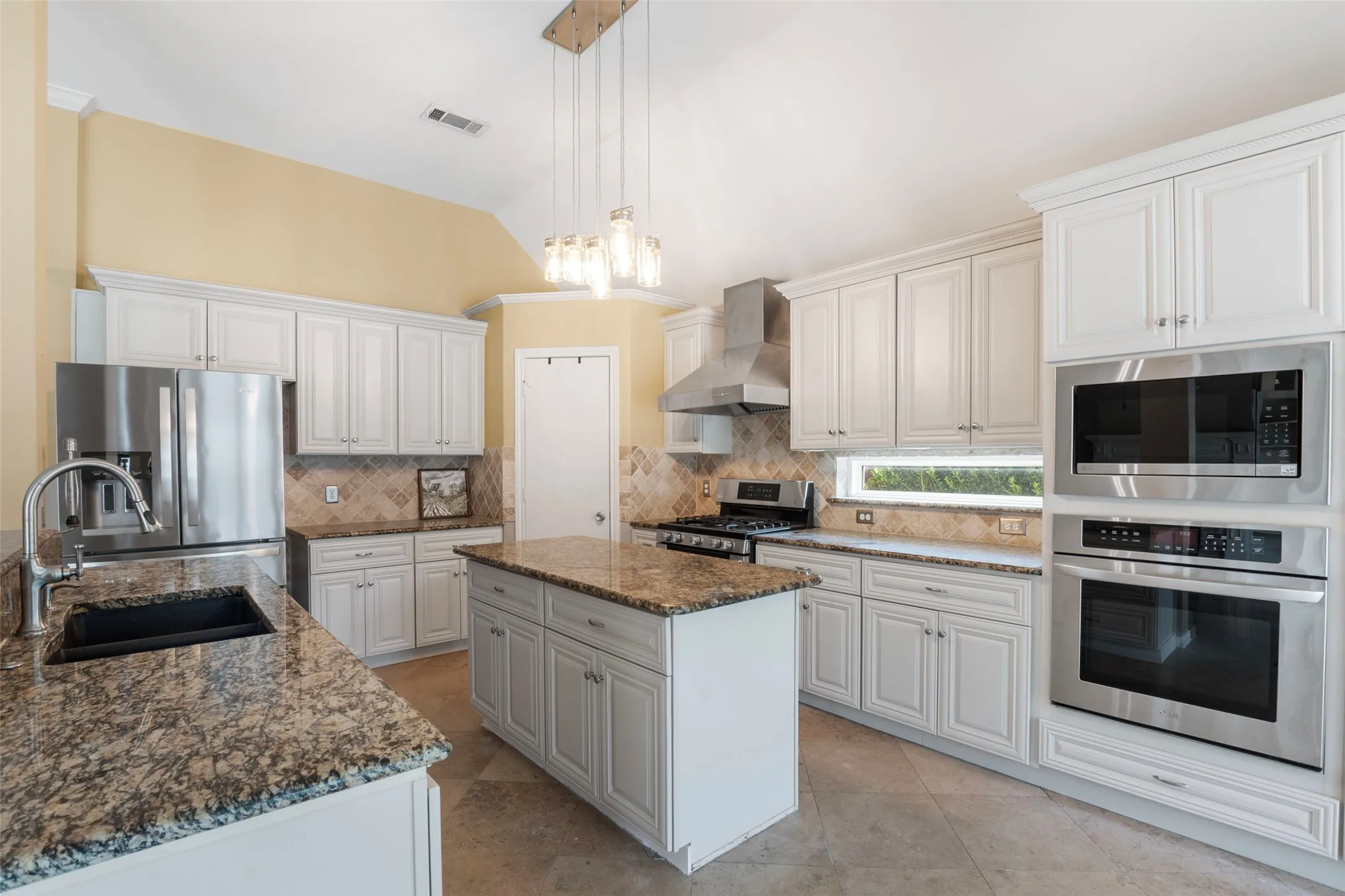 Kitchen featuring white cabinetry, granite countertops, stainless steel appliances, a center island, and tile flooring
