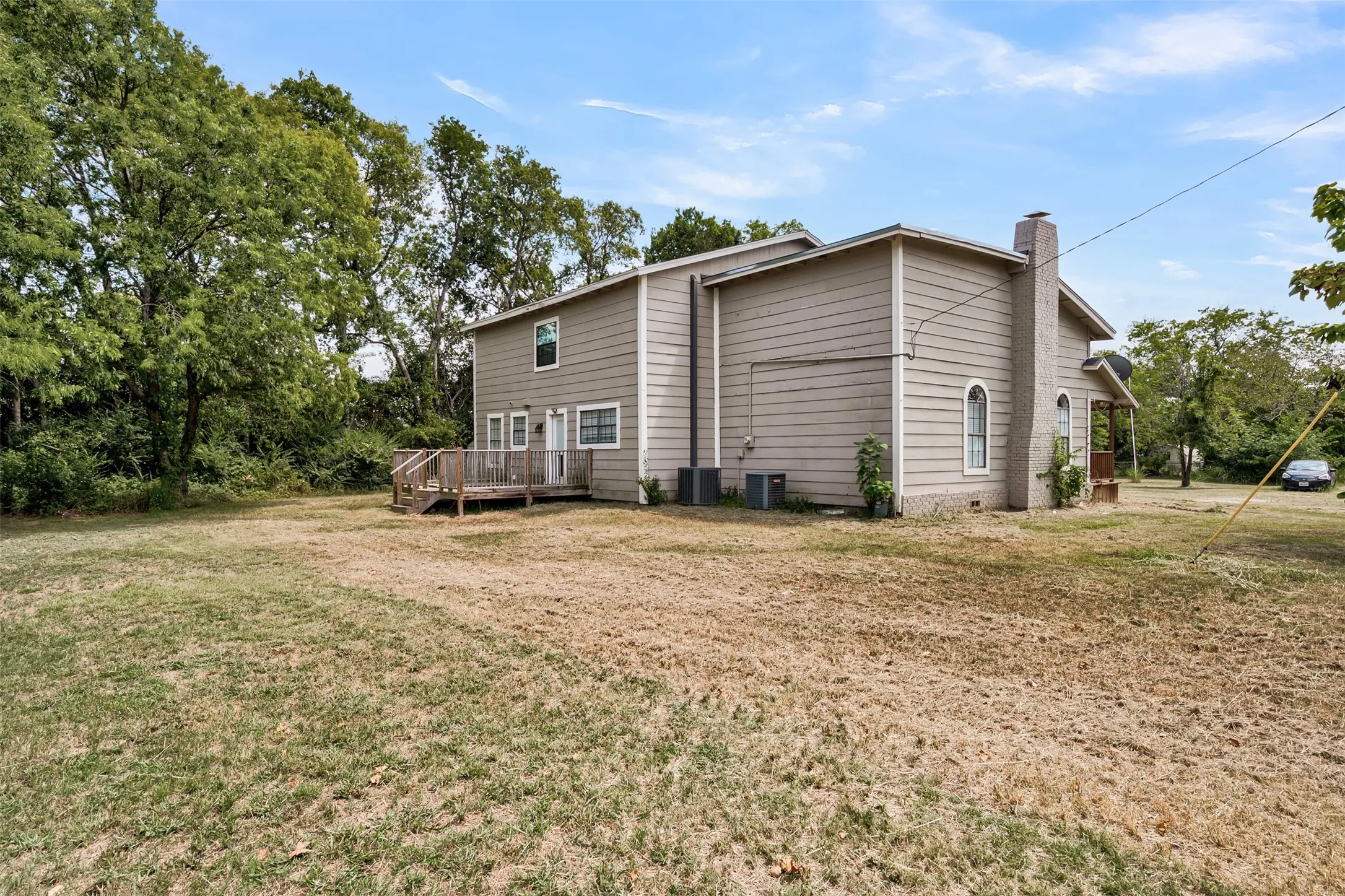 View of property exterior featuring a chimney, a yard, and a deck