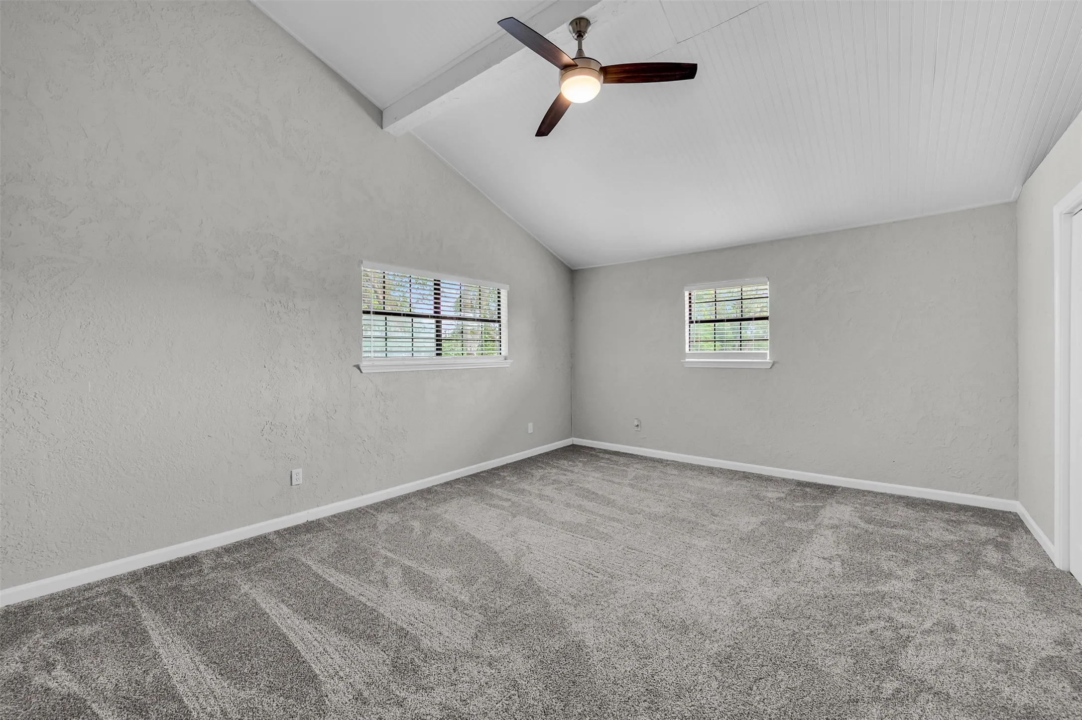 Carpeted spare room featuring a textured wall and ceiling fan