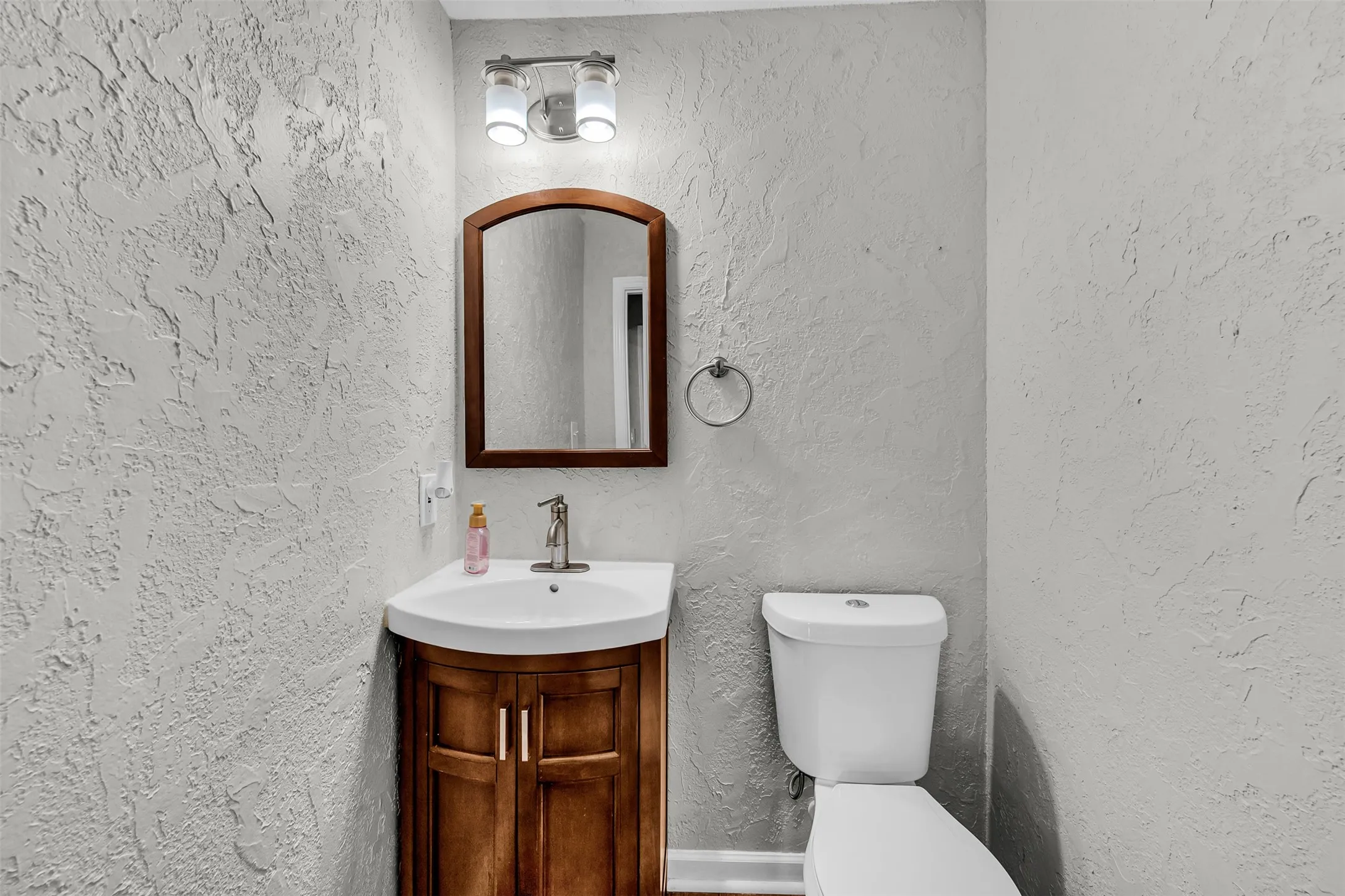 Half bathroom featuring a textured wall and vanity