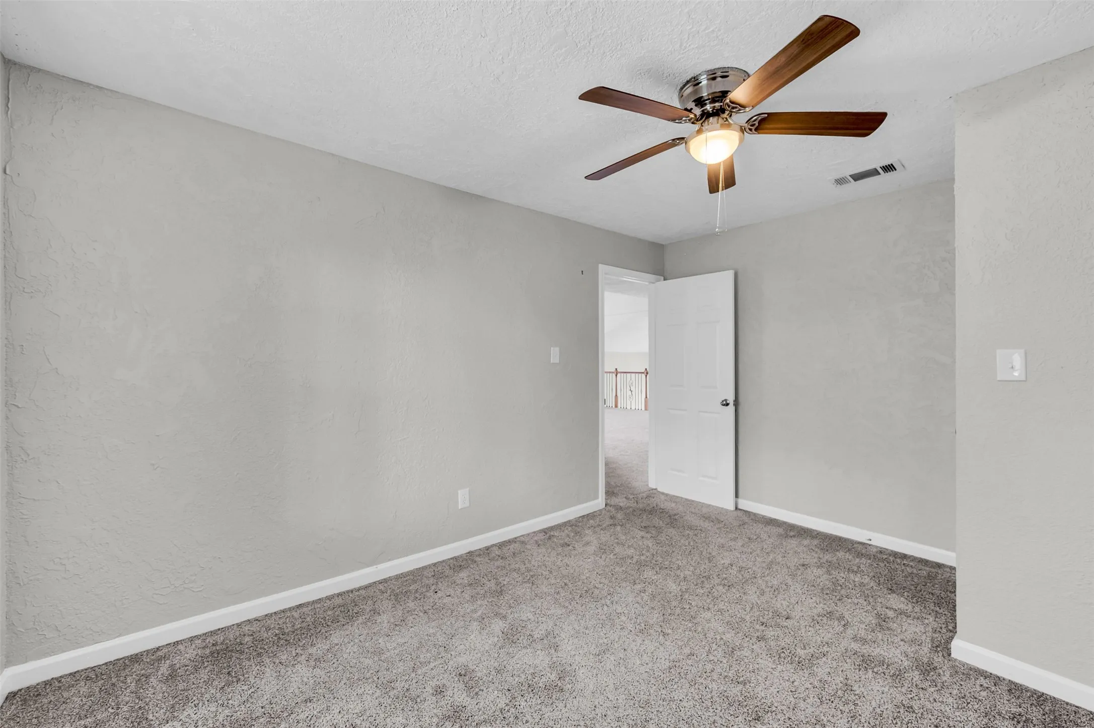 Spare room featuring carpet, a textured wall, a textured ceiling, and ceiling fan