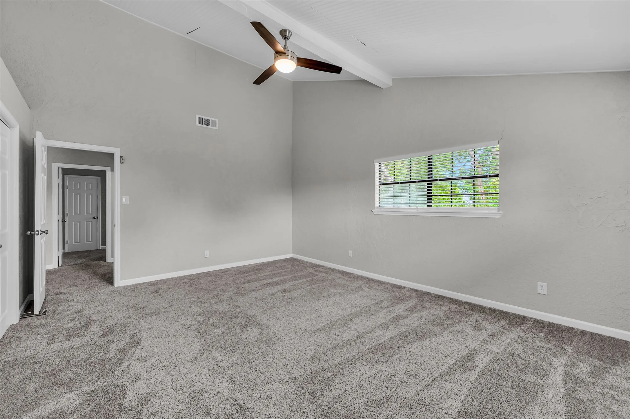 Empty room with light carpet, beam ceiling, a ceiling fan, and high vaulted ceiling