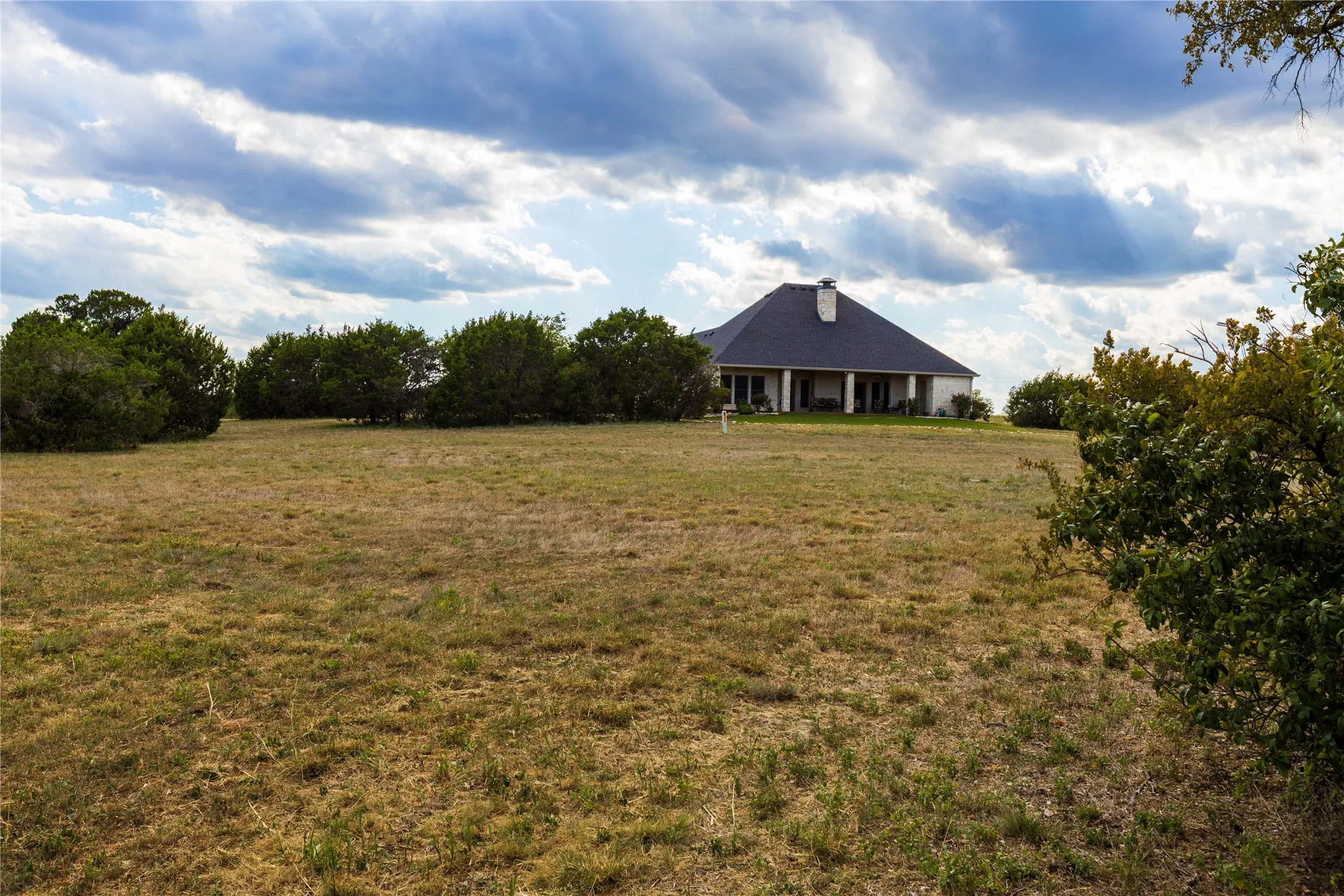 View of green lawn featuring a rural view and covered porch