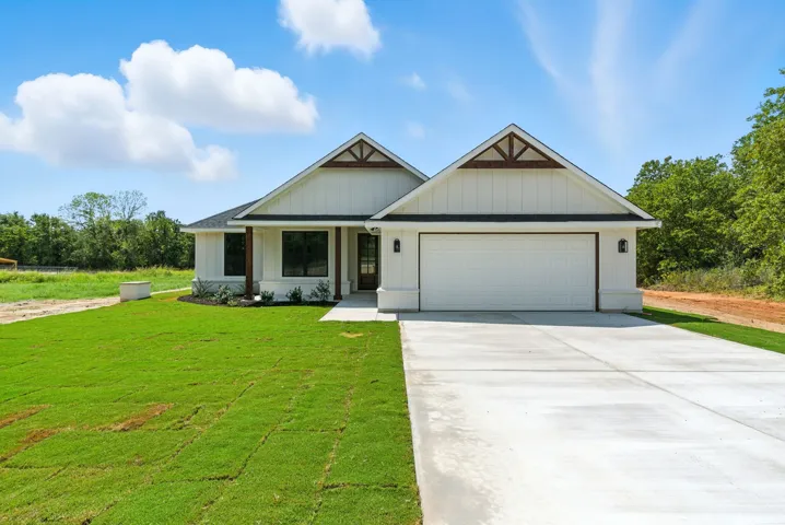 View of front facade with a garage, concrete driveway, a front lawn, and a porch