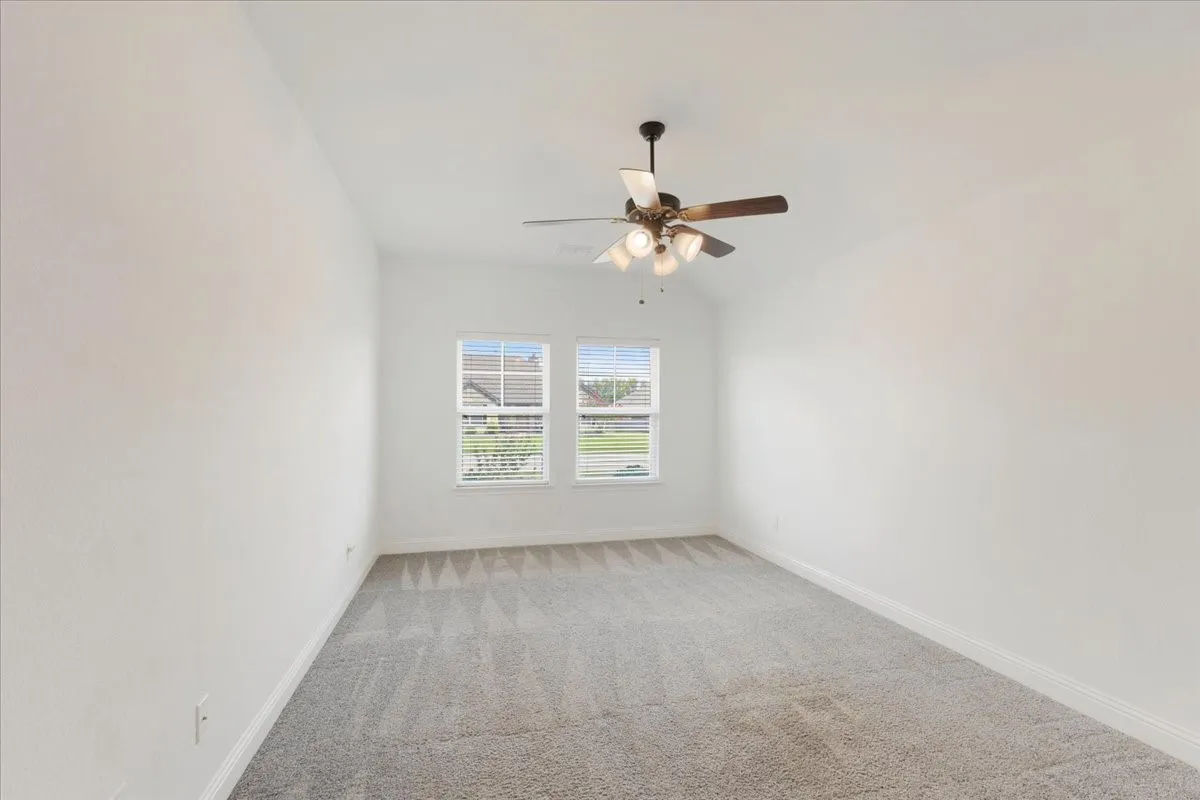 Third bedroom with double windows, carpet flooring, ceiling fan and walk in closet