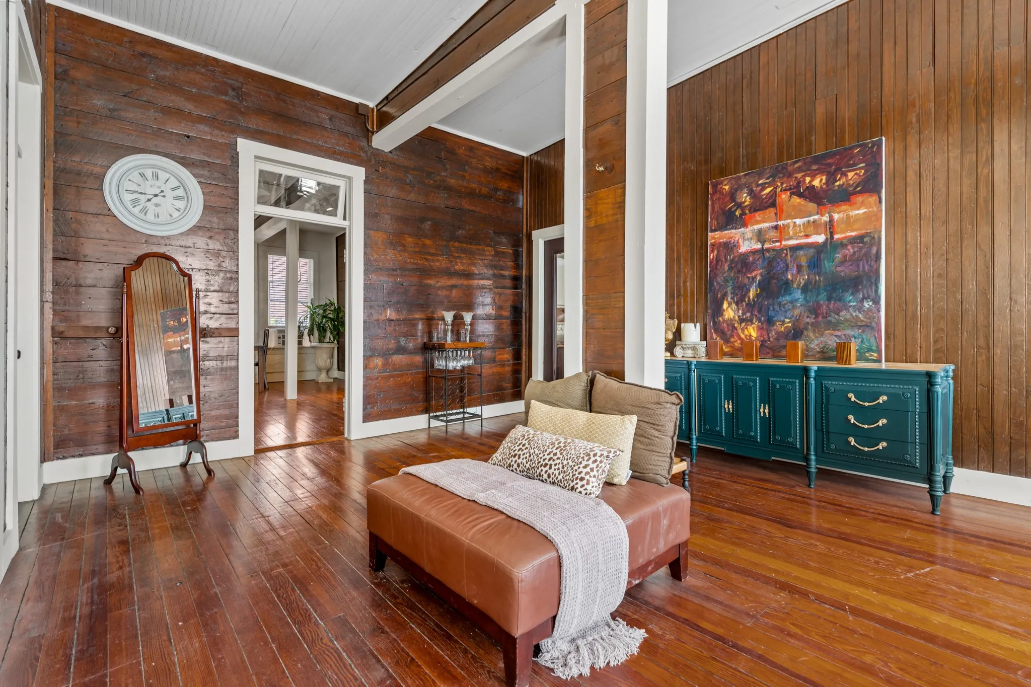 Living area featuring beamed ceiling, wooden walls, dark wood-style floors, and a towering ceiling