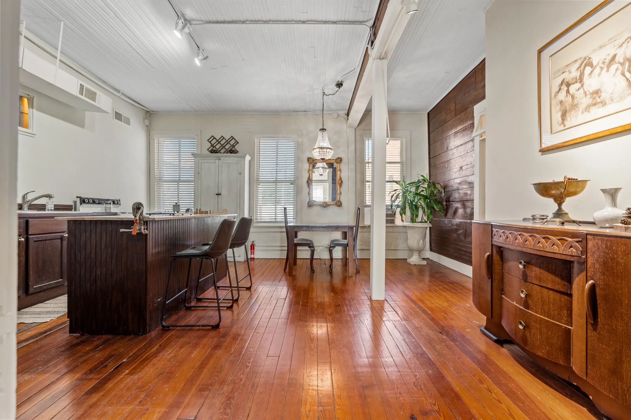 Bar area featuring dark wood finished floors, dark brown cabinetry, wooden walls, and pendant lighting