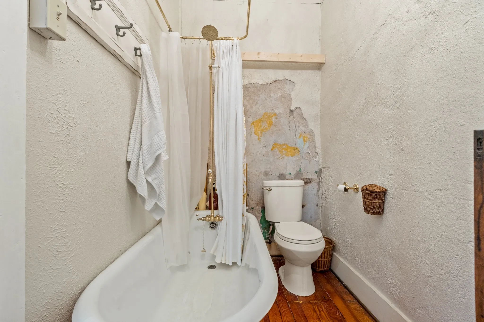 Full bathroom featuring a textured wall, dark wood-type flooring, and shower / bathtub combination with curtain