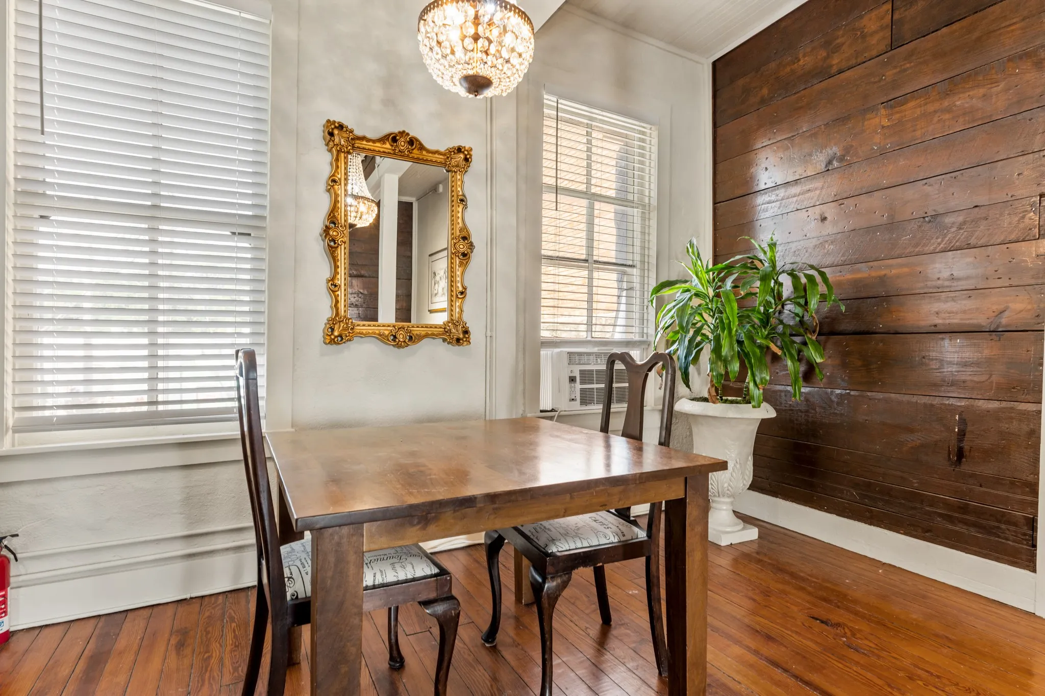 Dining space featuring wood-type flooring, wood walls, and a chandelier