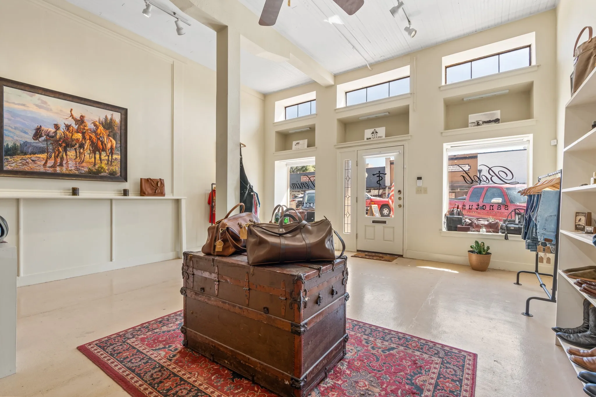 Living room featuring rail lighting, a ceiling fan, and a towering ceiling